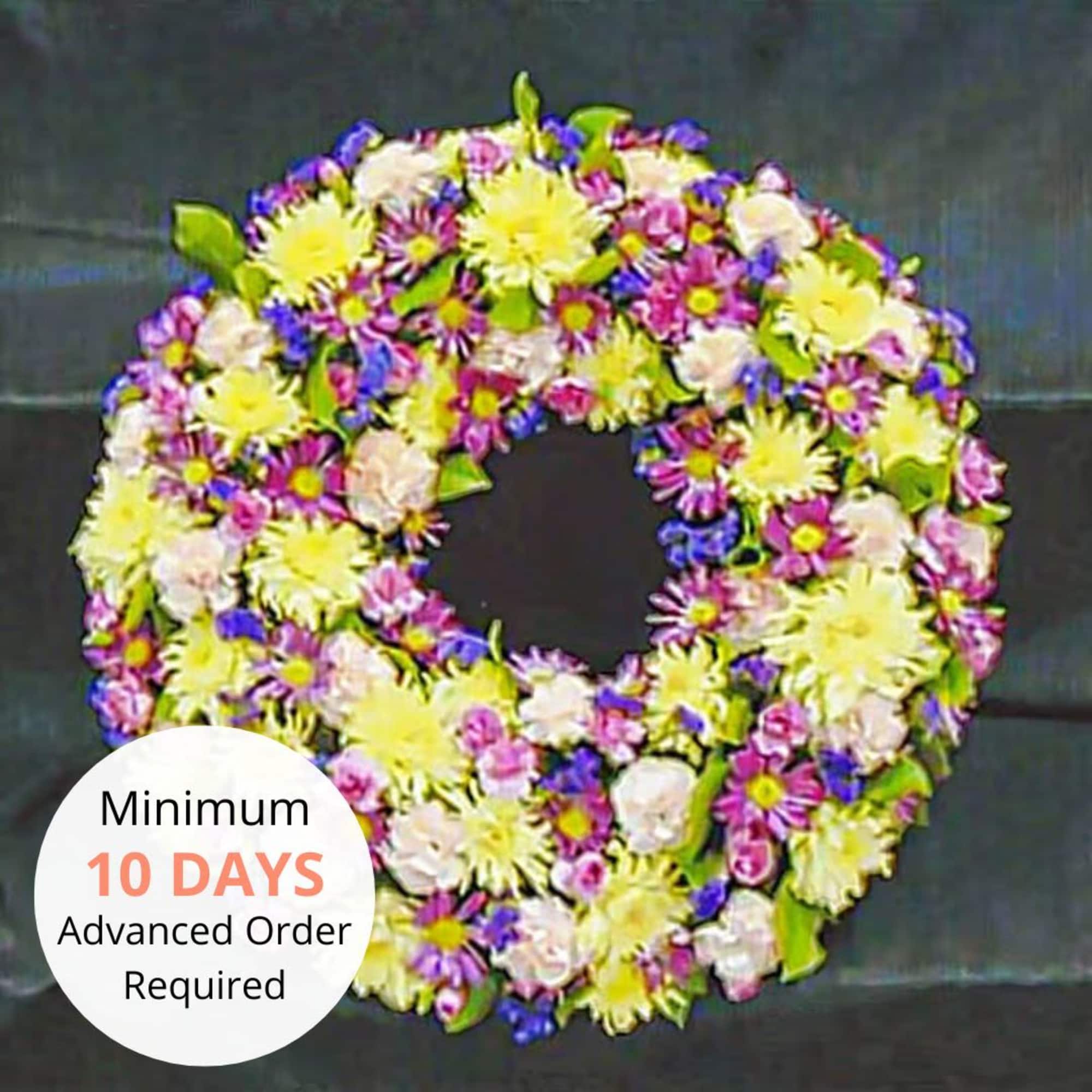 Round wreath of yellow, pink, and purple flowers against a dark background