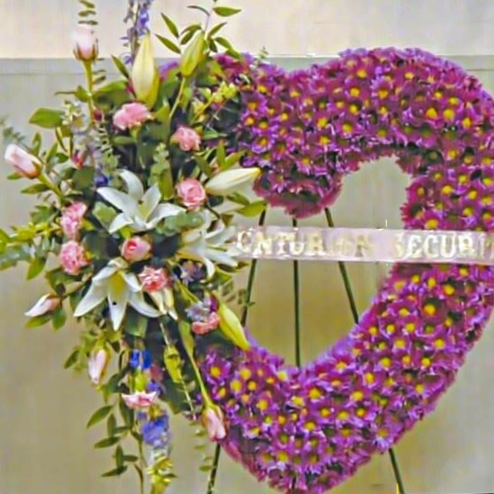 Standing heart-shaped purple funeral wreath with white lilies and pink roses on one side.