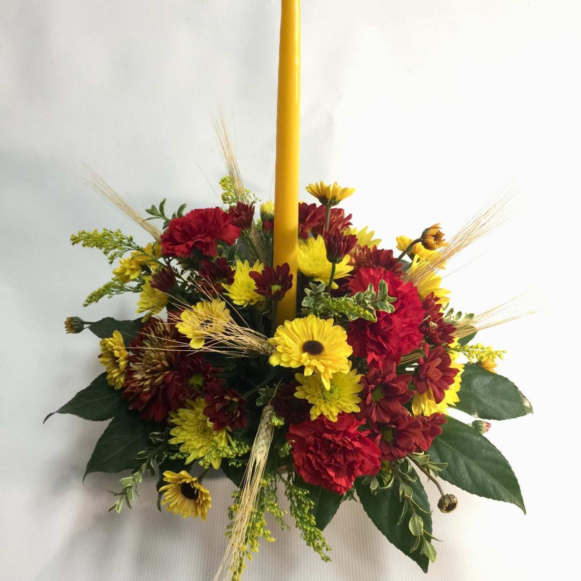 Red and yellow floral centerpiece with a tall yellow candle