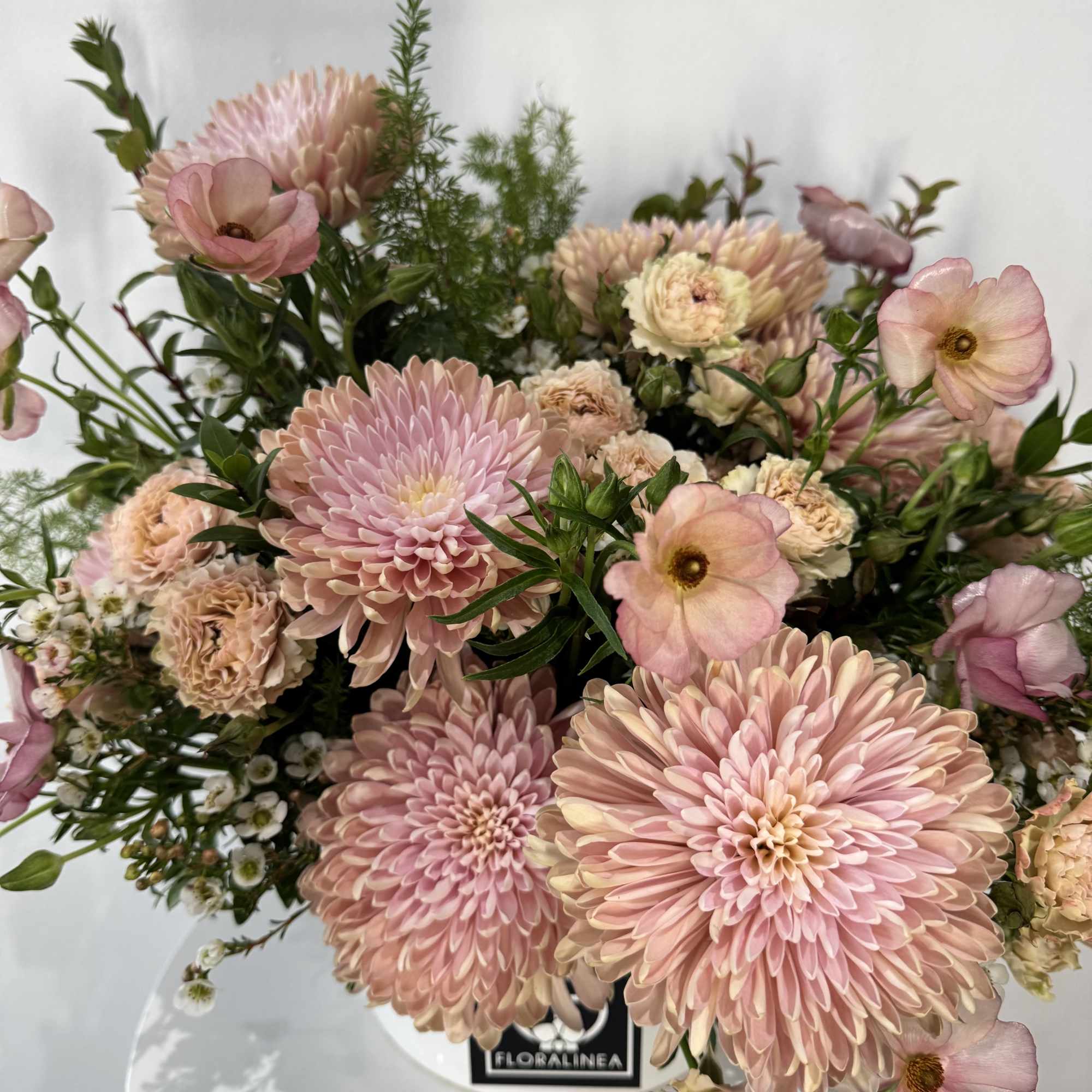 Pink chrysanthemum bouquet with pale peach blooms in a white vase