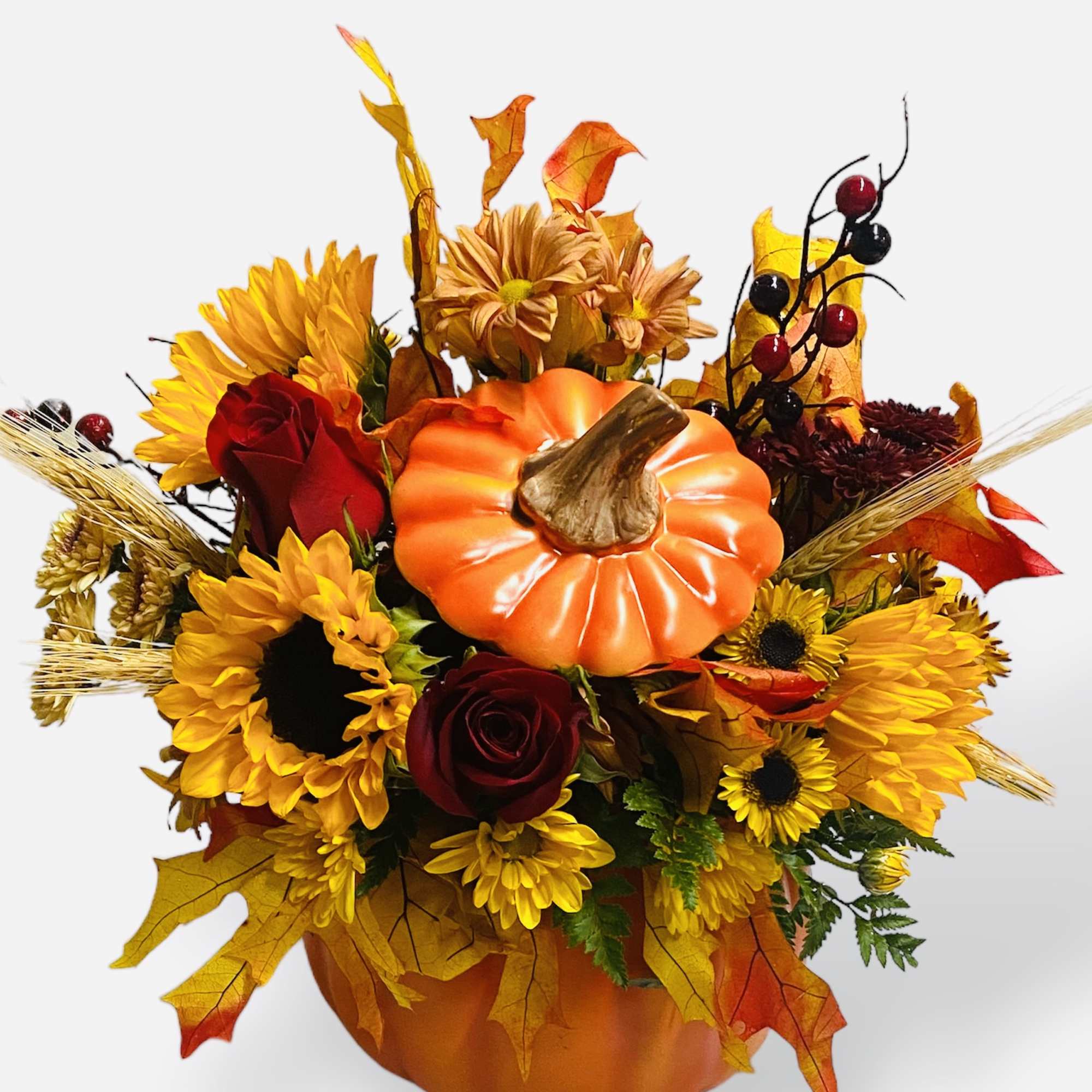 Fall floral arrangement in a pumpkin container with sunflowers and red roses