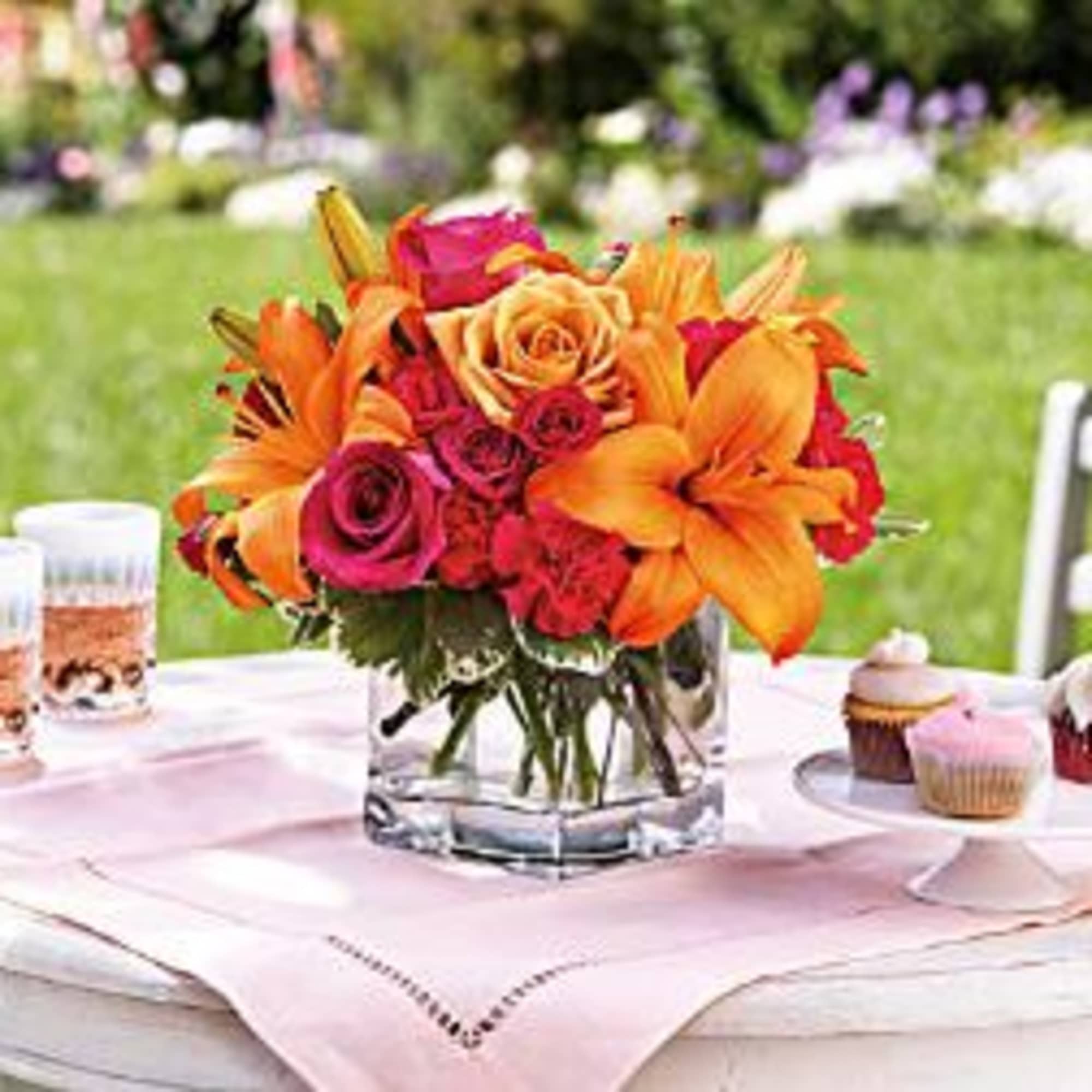 Orange and pink floral centerpiece in a clear glass vase on a table