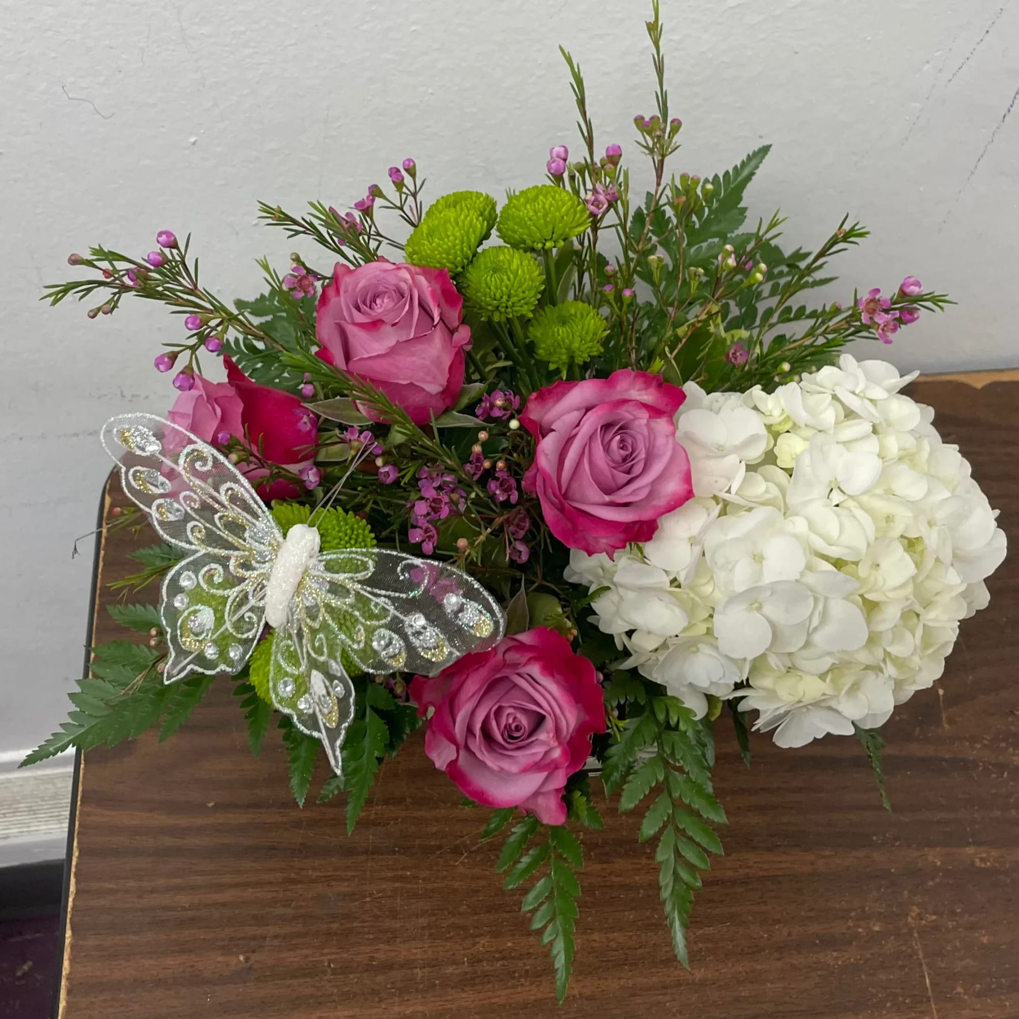 Pink roses and white hydrangea arrangement with a decorative butterfly