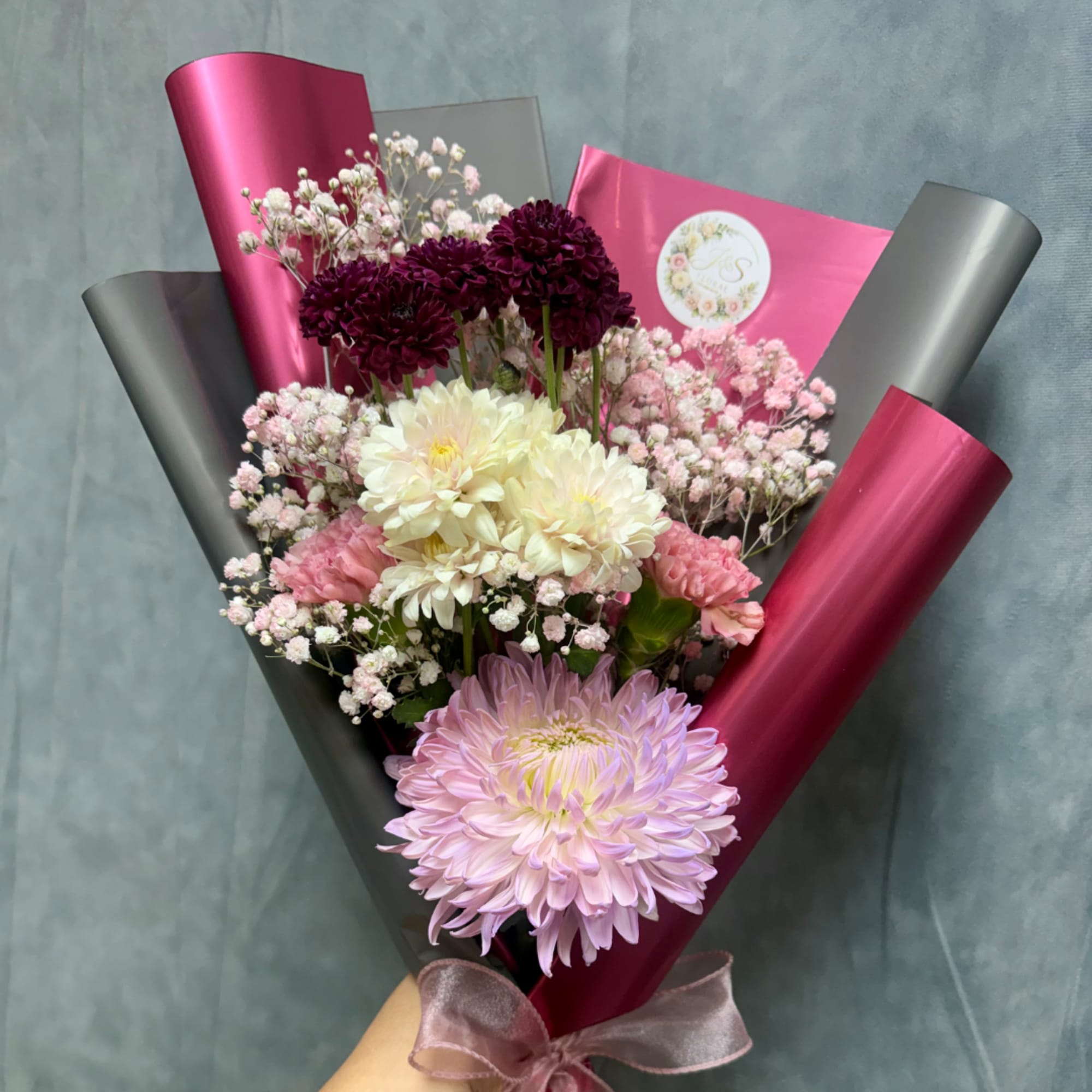 Bouquet of chrysanthemums and baby's breath wrapped in pink and gray paper