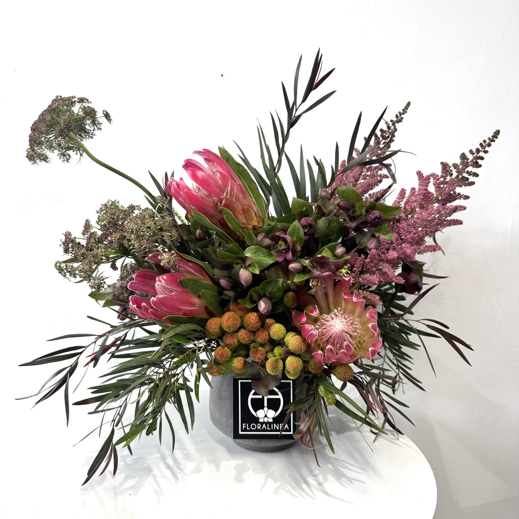 Pink protea arrangement in a gray container