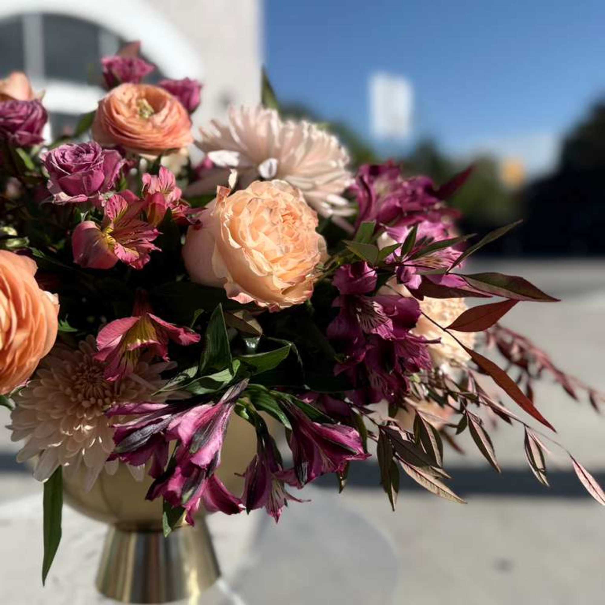 Bouquet of peach and purple flowers in a metallic vase