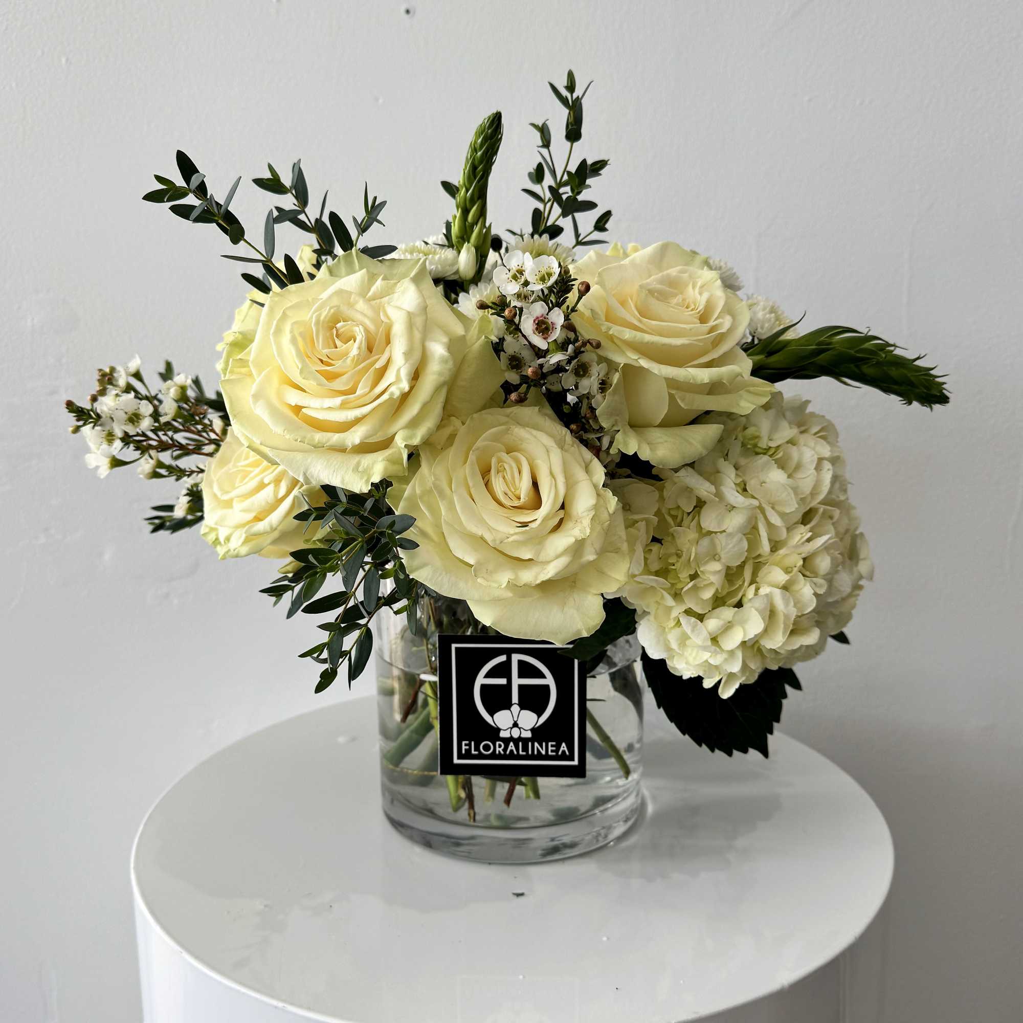 Cream rose bouquet with white hydrangea in a clear glass vase