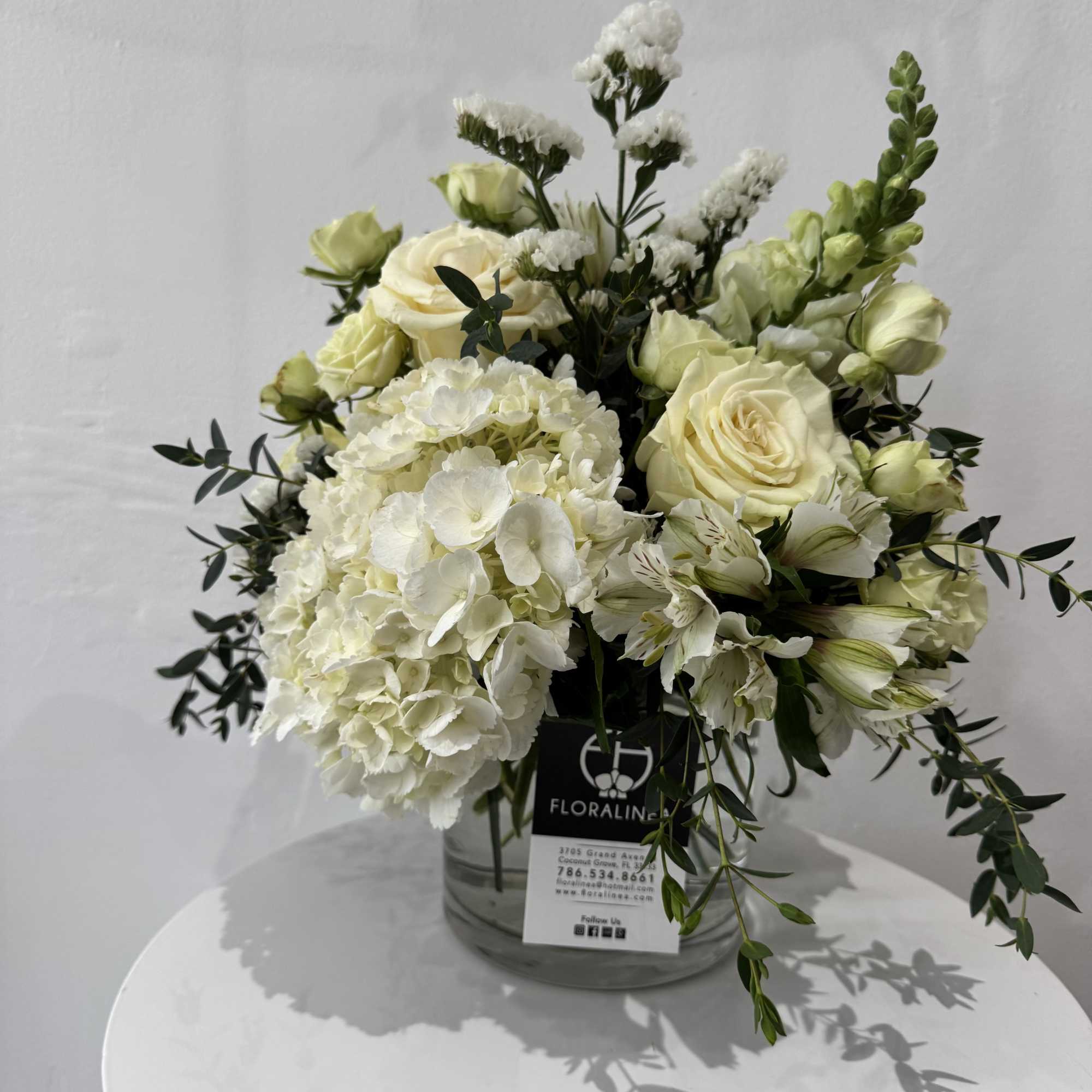 White and pale yellow floral arrangement in a glass vase