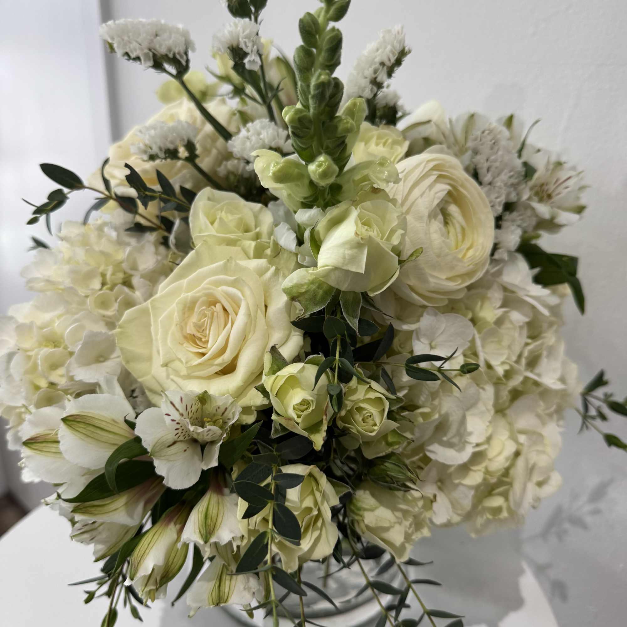 White and pale green bouquet with roses, hydrangeas, and trailing greenery