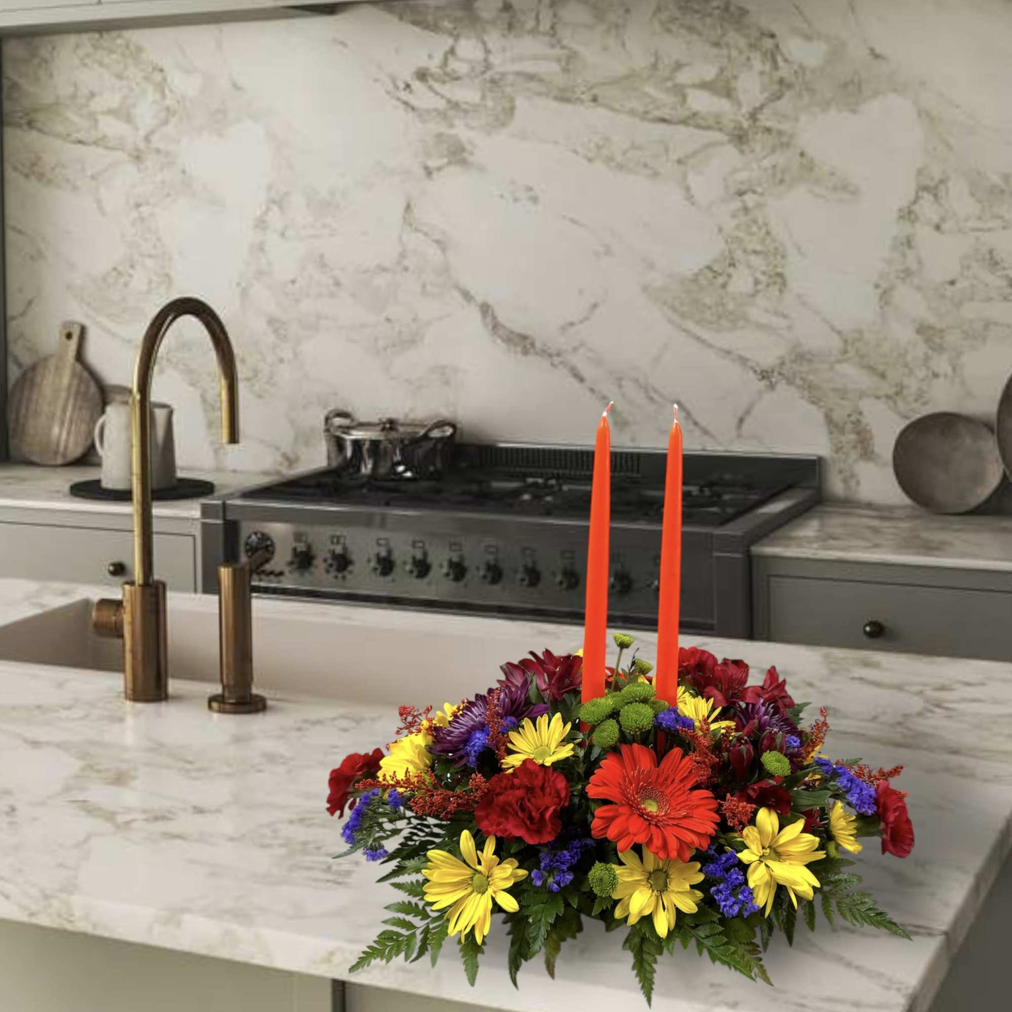 Colorful flower centerpiece with two orange candles on a kitchen island