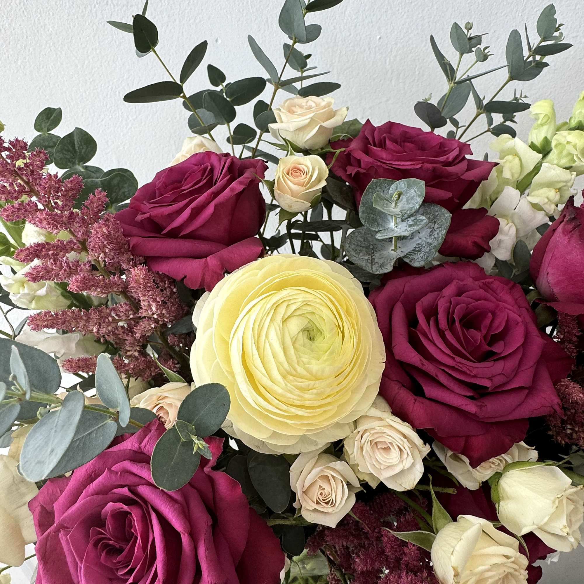 Bouquet of magenta and cream roses with a pale yellow ranunculus