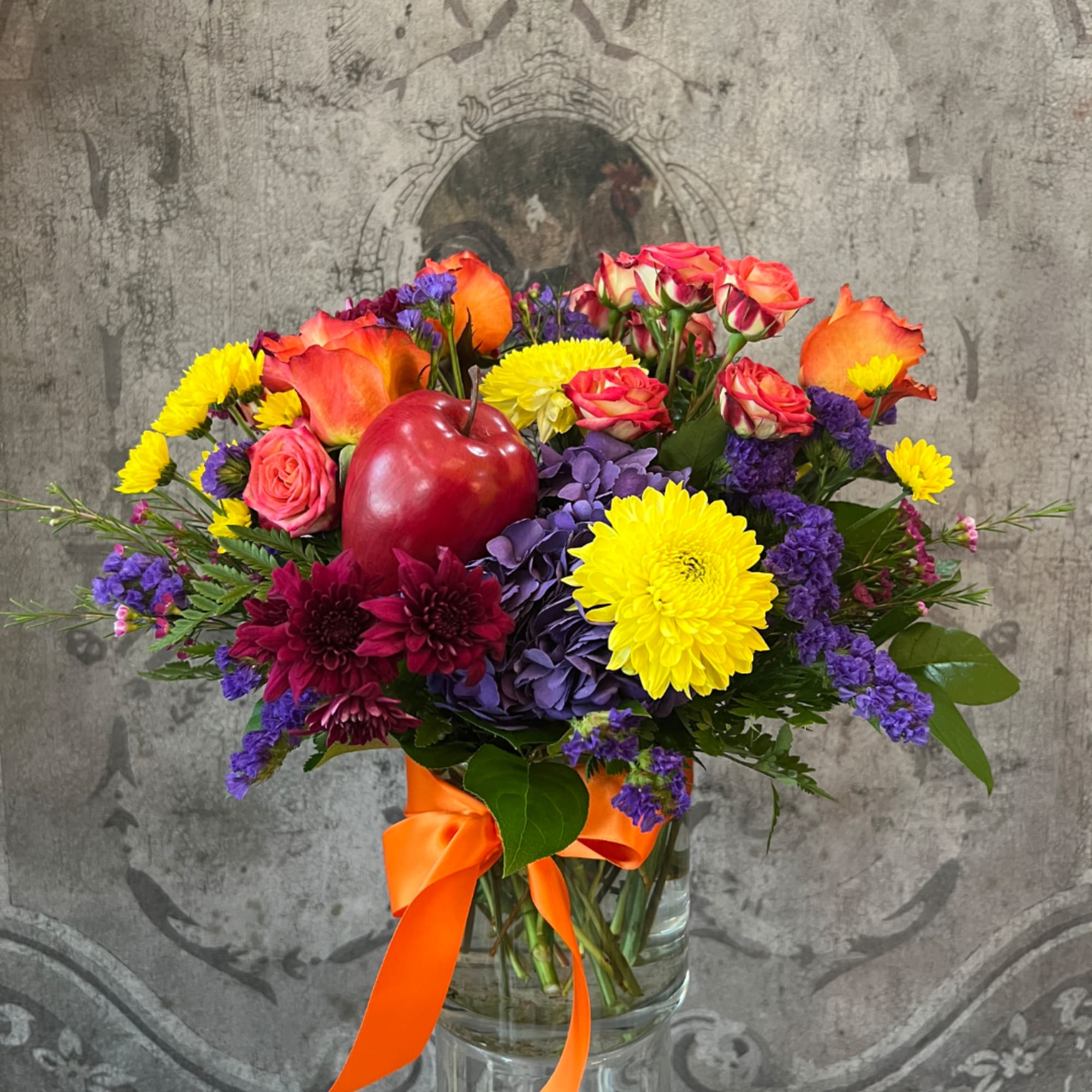 Colorful mixed bouquet in a clear glass vase with an orange ribbon