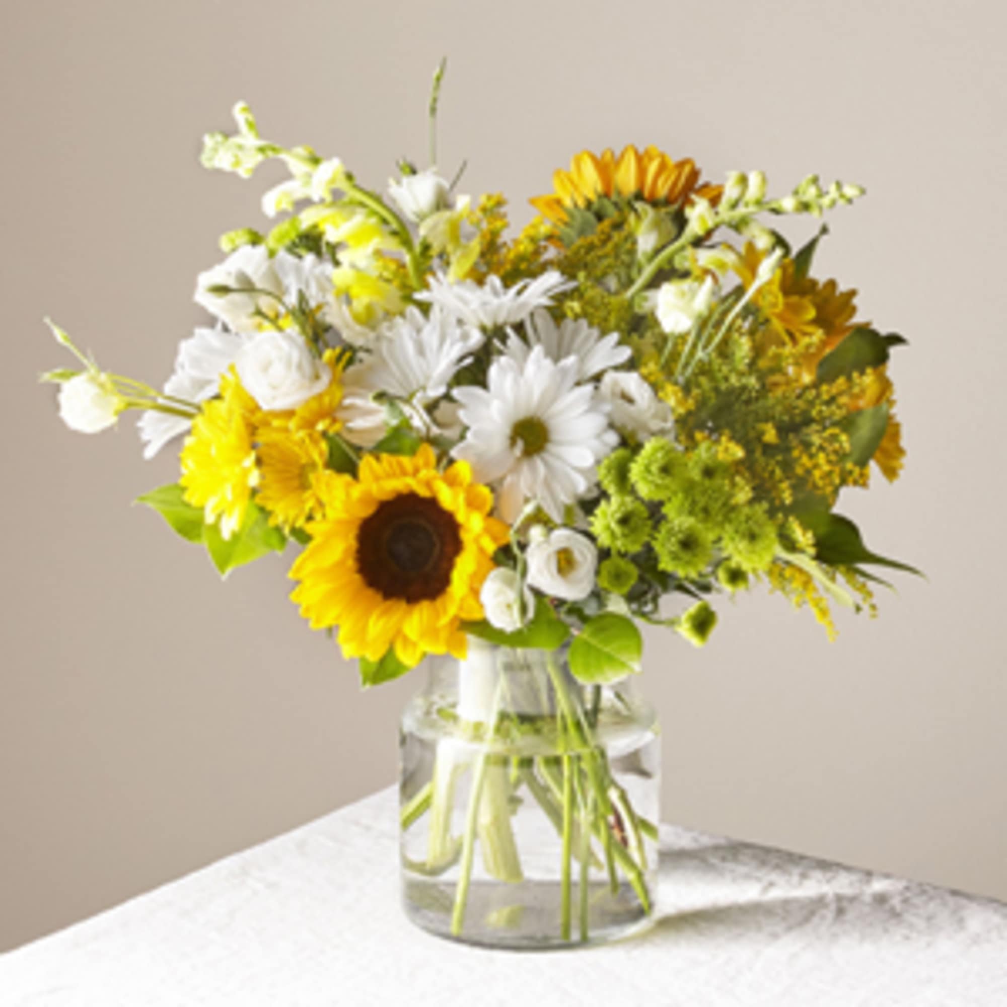 Bouquet of sunflowers and white daisies in a clear glass vase