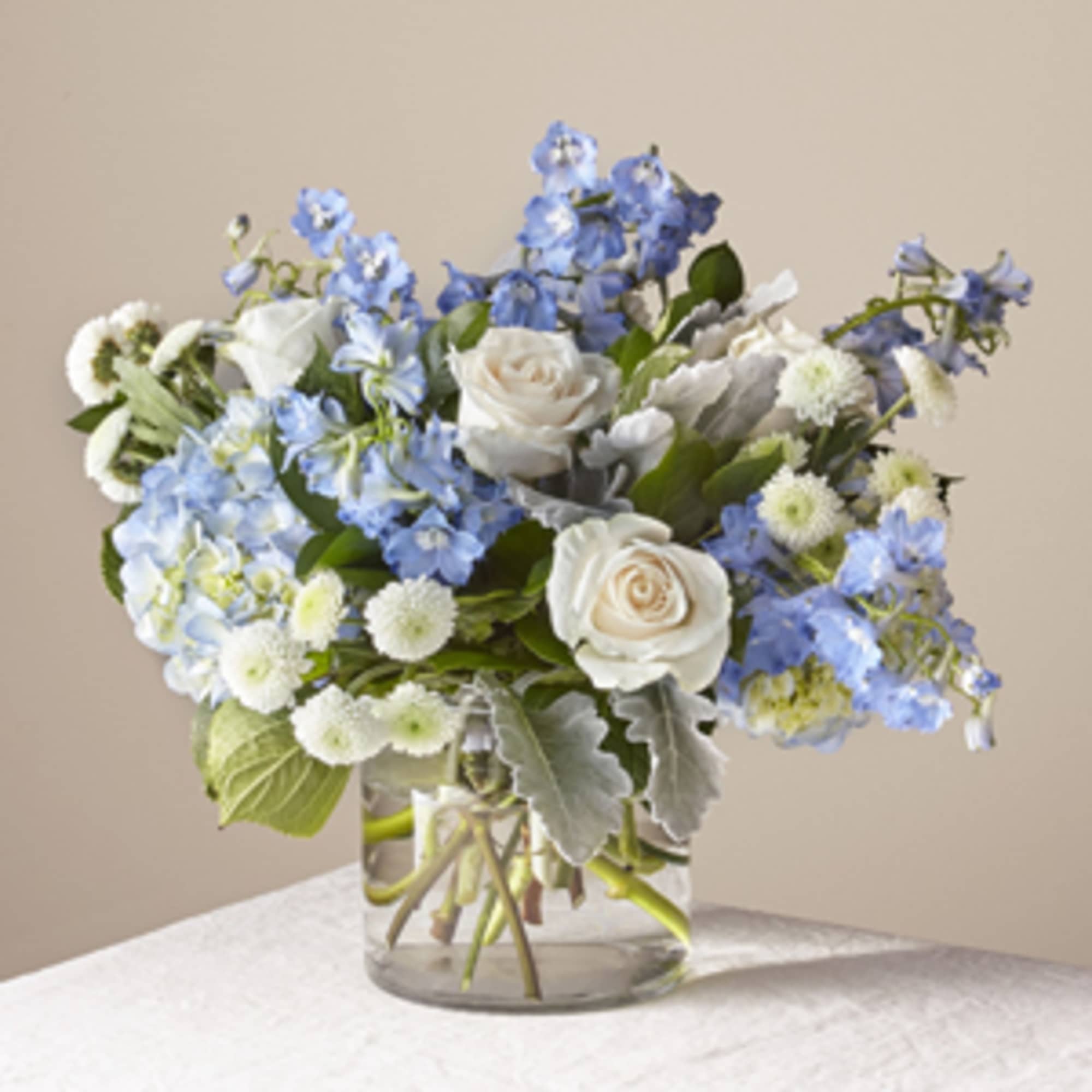 Blue and white bouquet of roses and delphinium in a clear glass vase