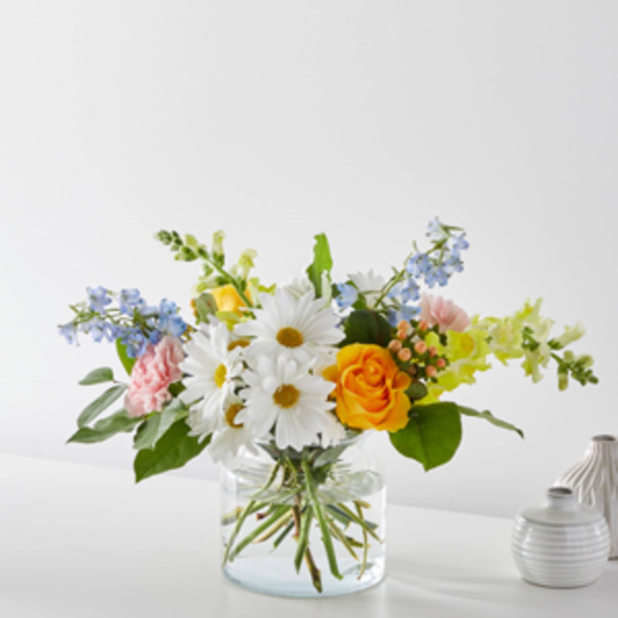Bouquet of daisies, roses, and pastel flowers in a clear glass vase