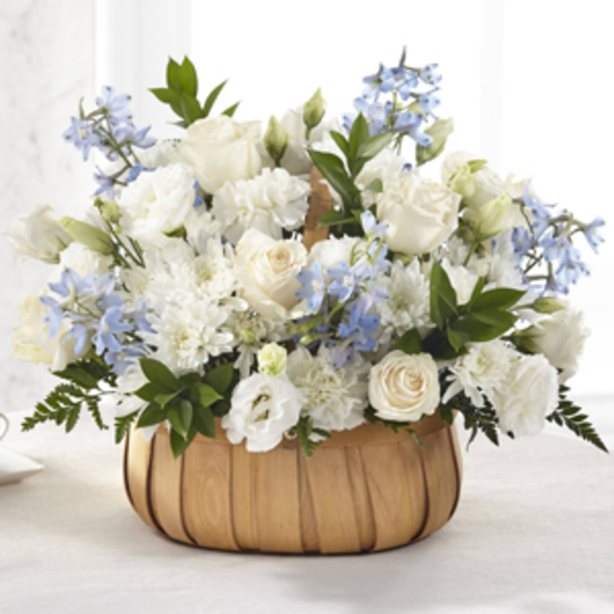 White and pale blue flowers arranged in a wooden basket