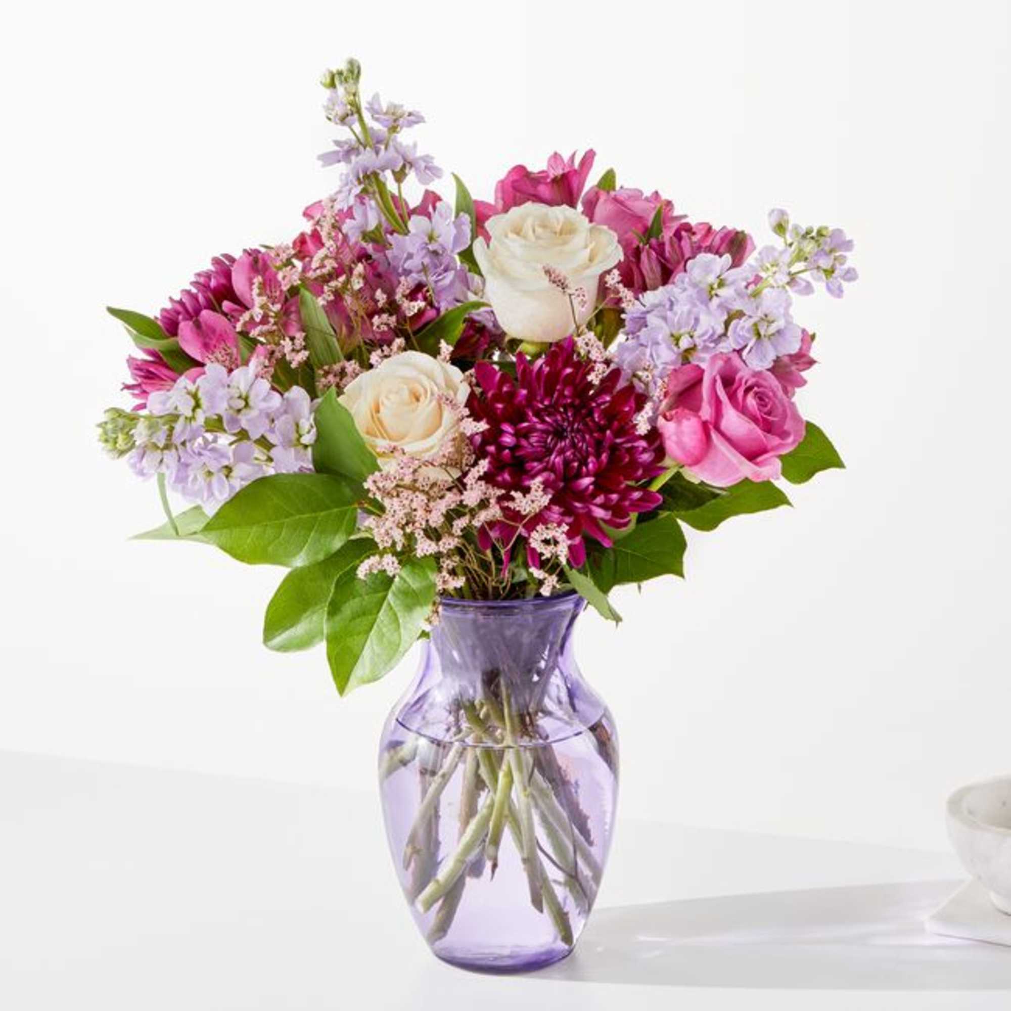 Pink and lavender mixed bouquet in a purple glass vase