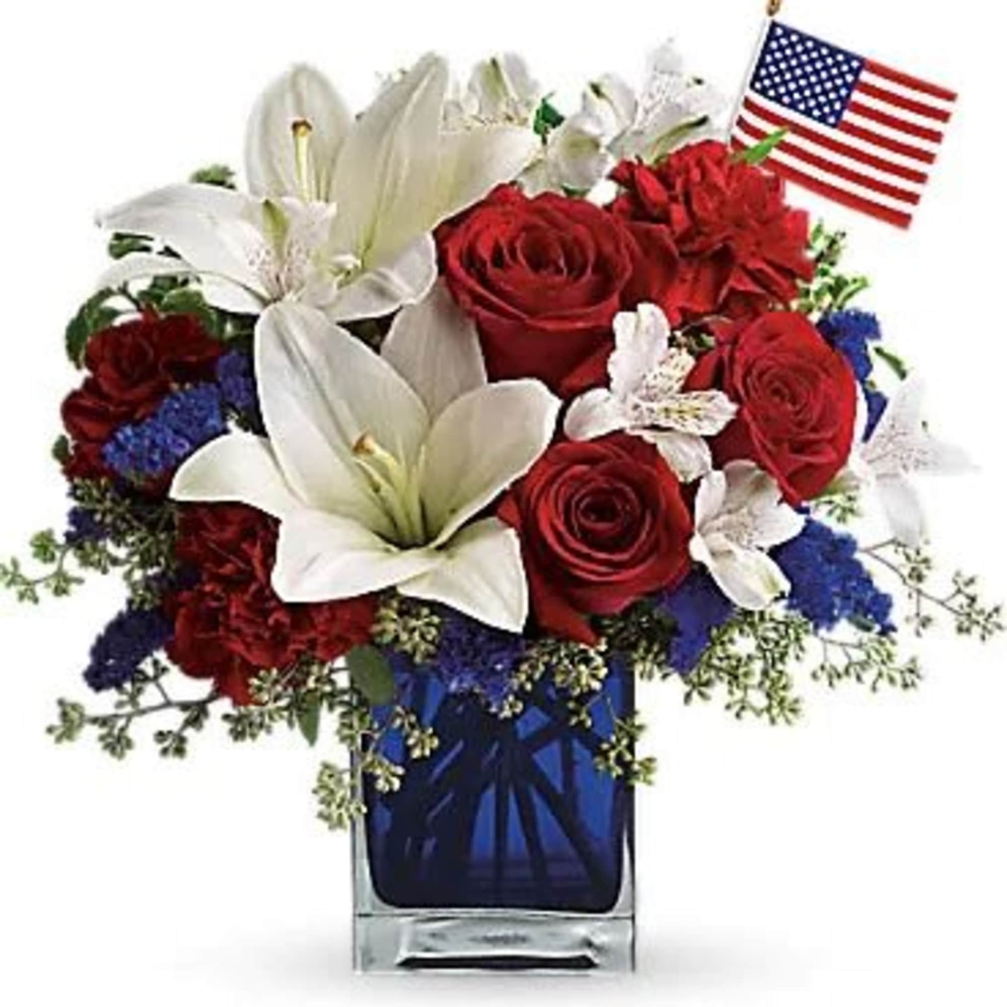Red roses and white lilies in a blue glass vase with a small American flag