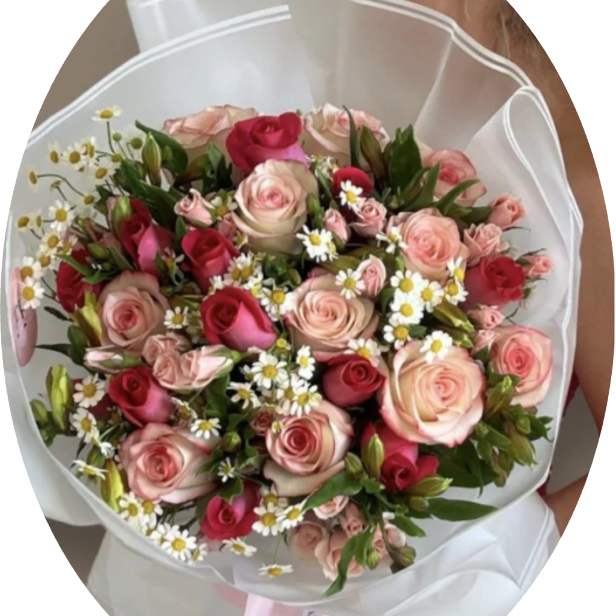 A lush hand-tied bouquet of blush pink and deep red roses framed