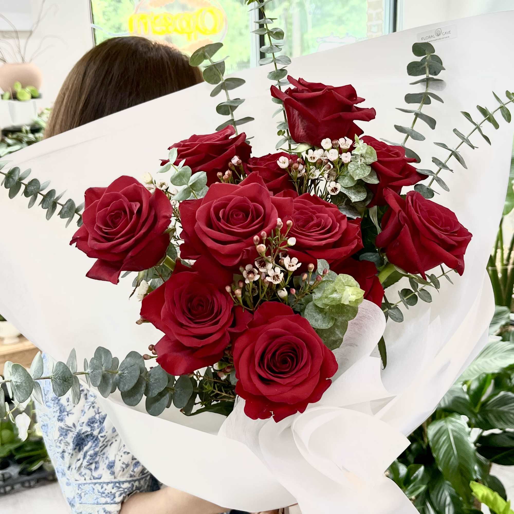 A dense cluster of deep red roses arranged in a rounded, hand-tied