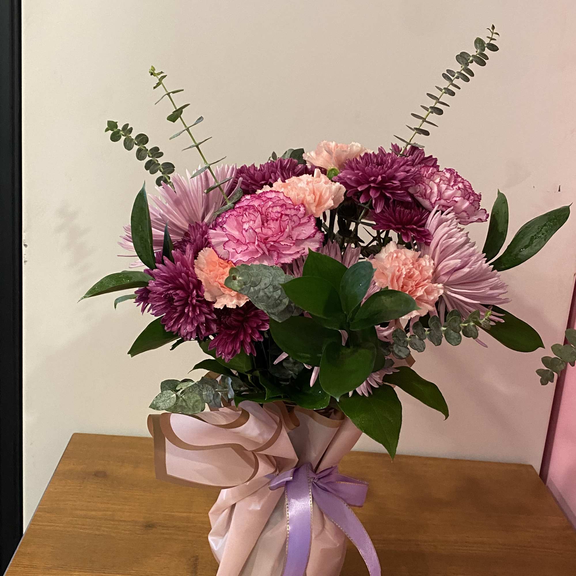 Pink and purple mixed bouquet in wrapped paper with a ribbon