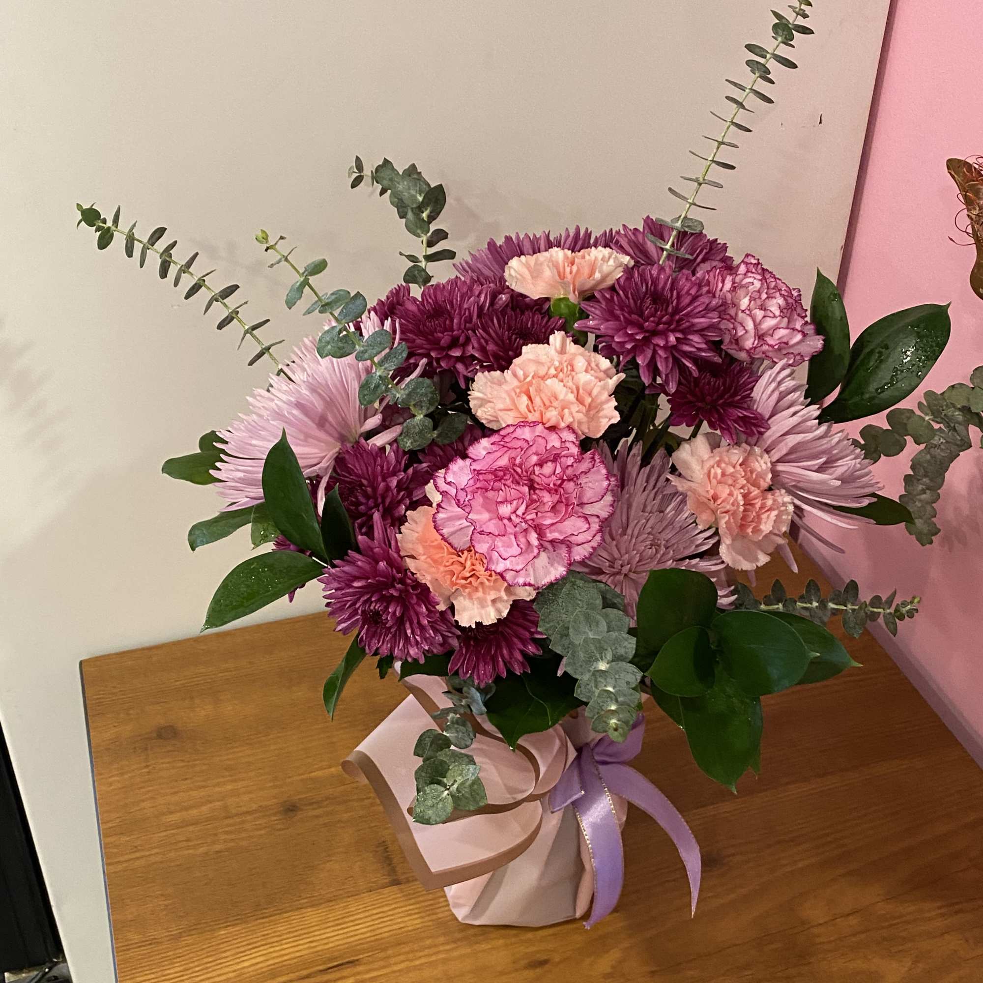 Bouquet of pink and purple flowers in a wrapped box with ribbon