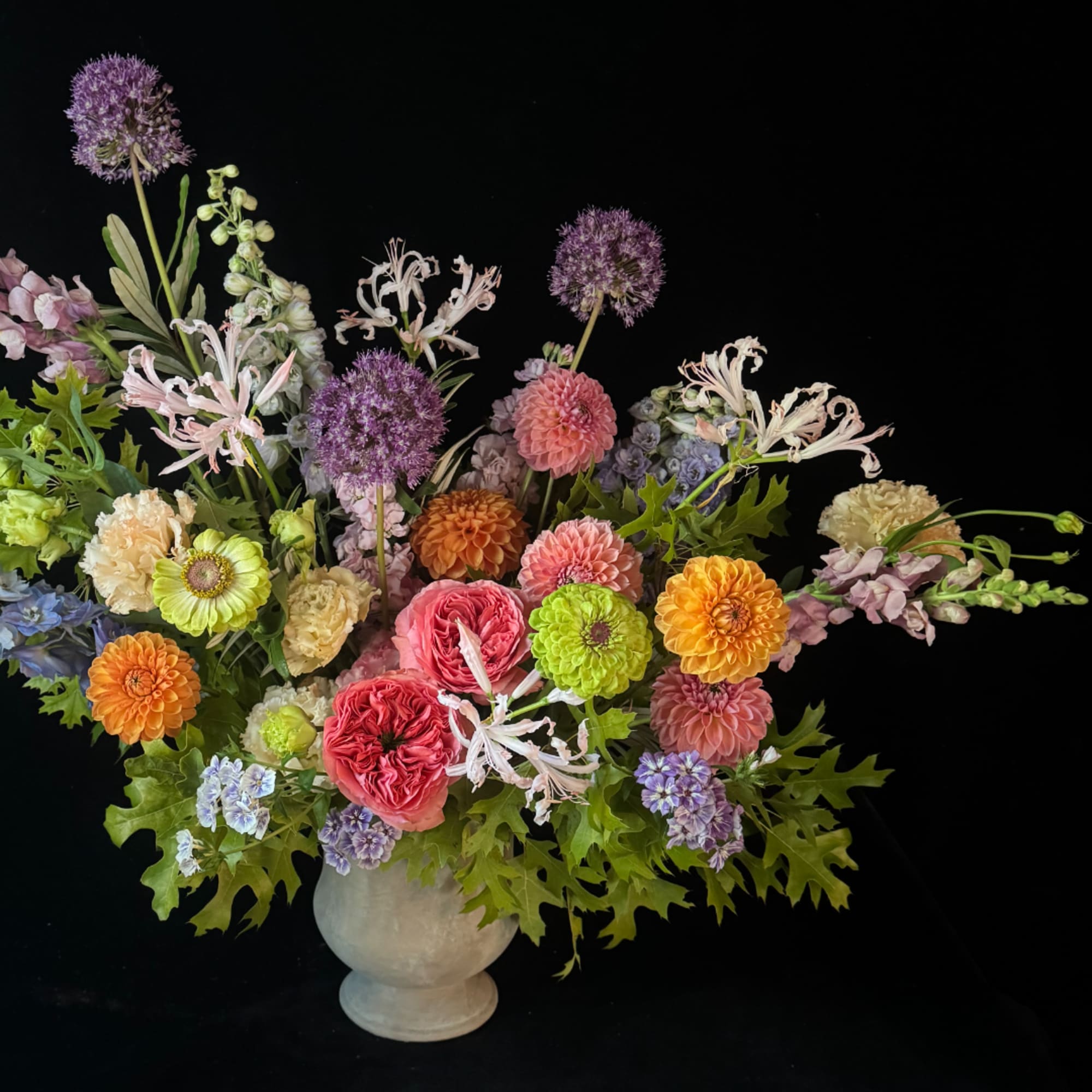 Colorful mixed flower arrangement in a white vase on a black background