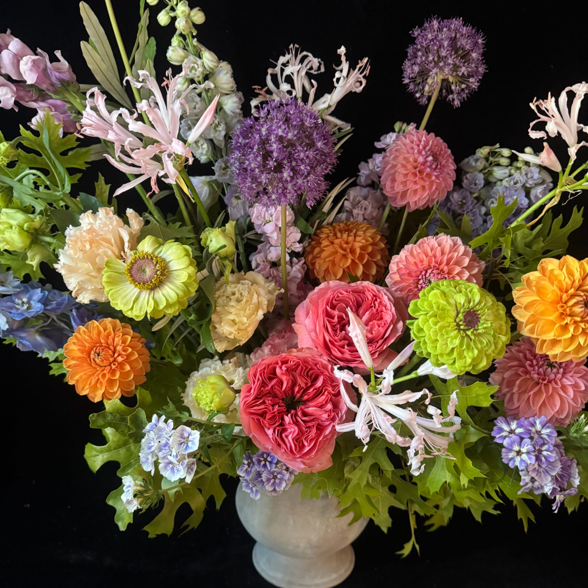 Colorful mixed flower arrangement in a white vase with pink, purple, orange, and green blooms