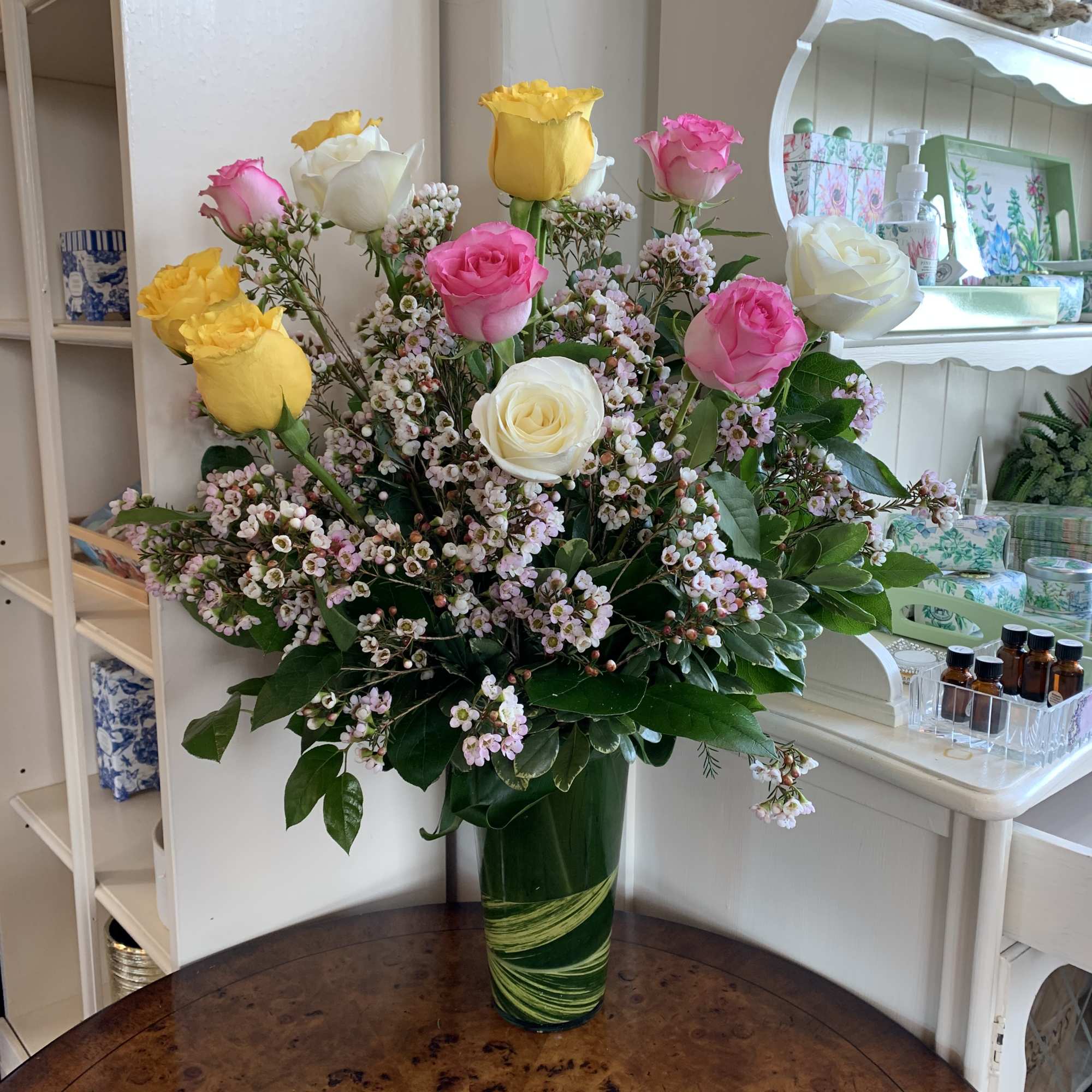 Bouquet of pink, yellow, and white roses in a green glass vase