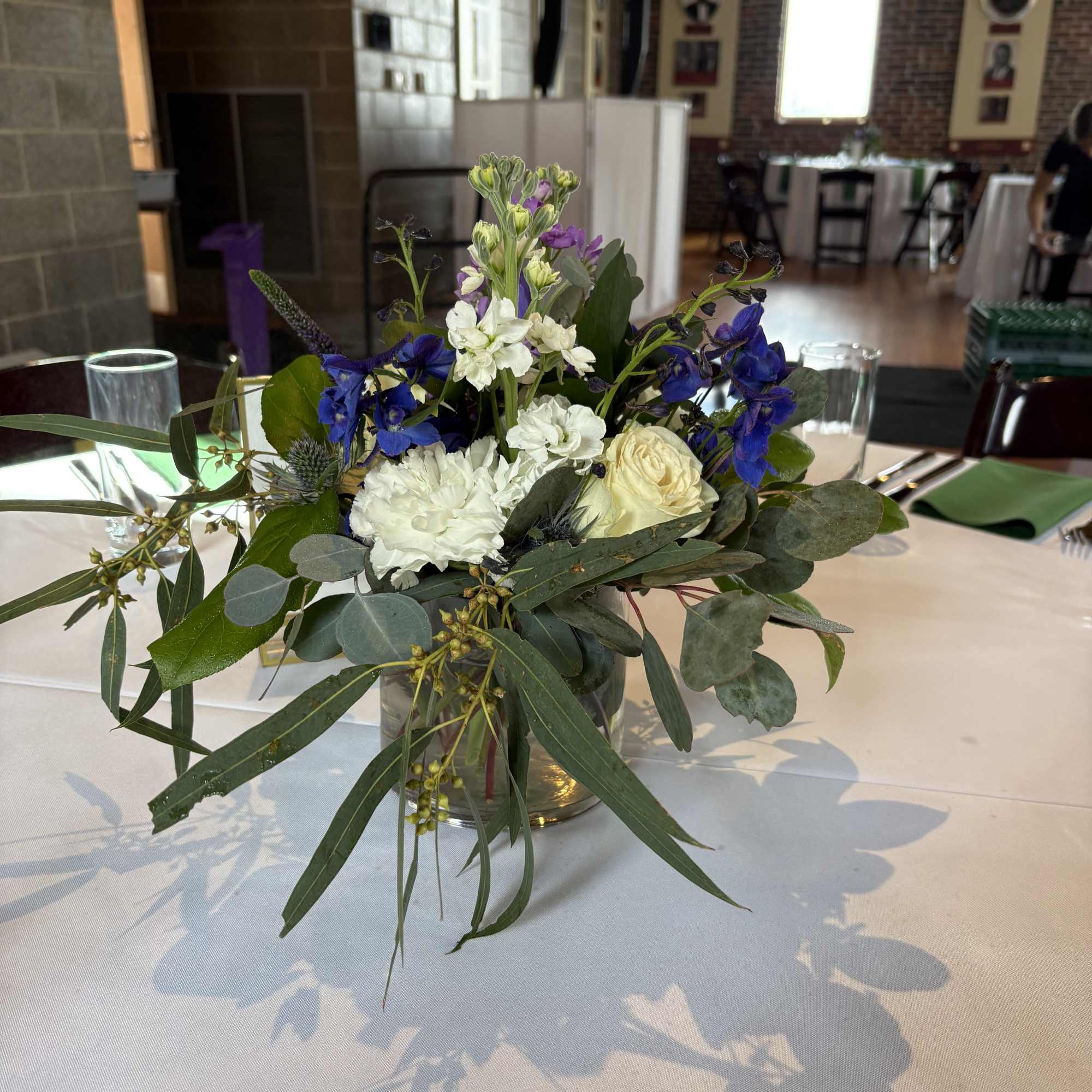 Blue and white floral centerpiece in a glass vase on a table