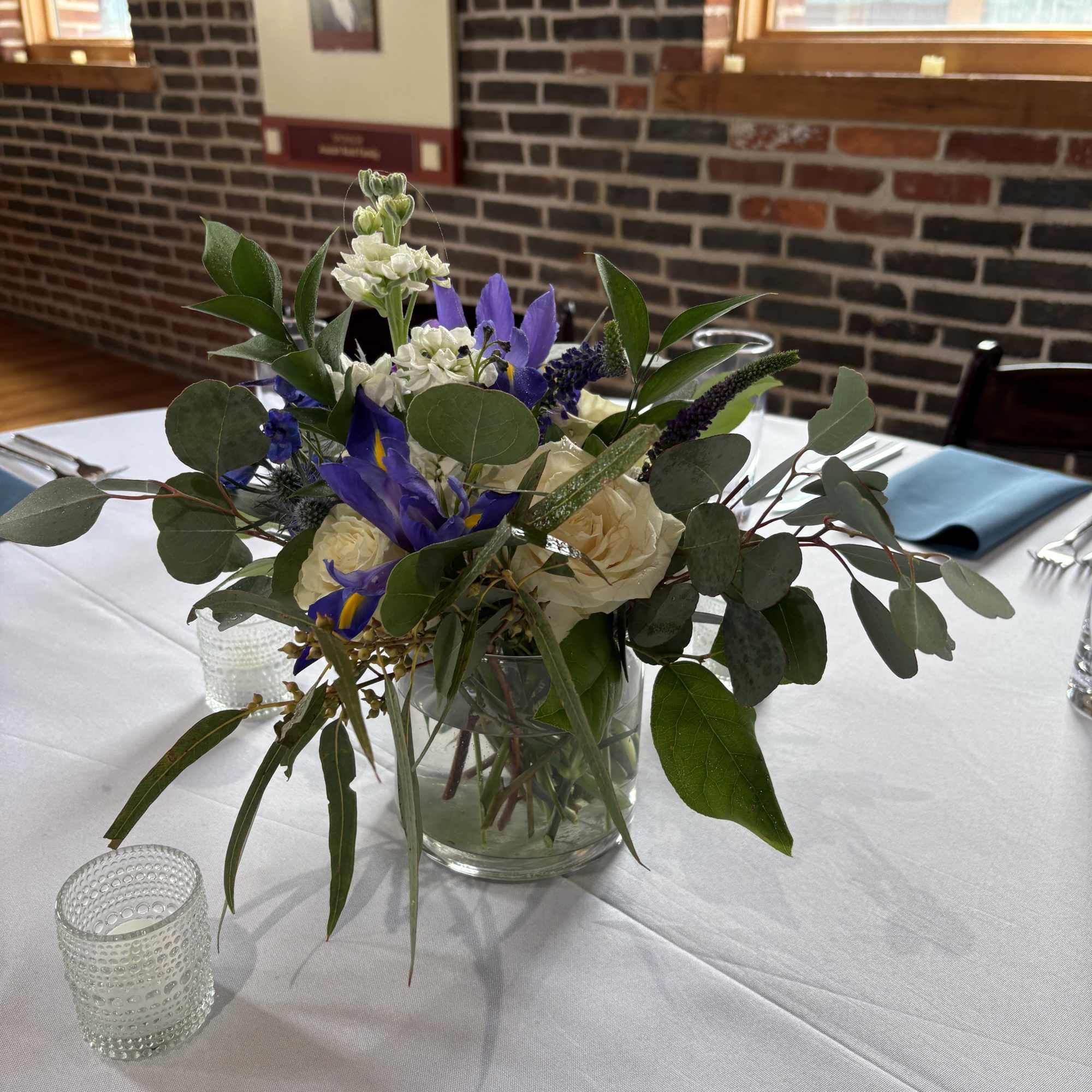 Blue and white floral centerpiece in a clear glass vase