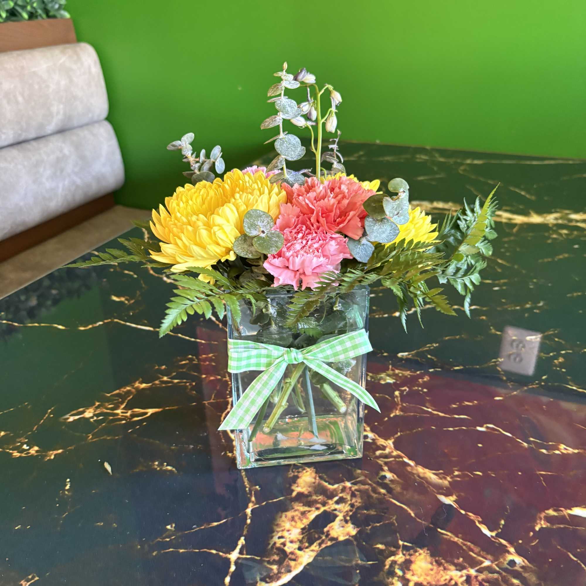 Colorful flower arrangement in a square glass vase with a gingham ribbon