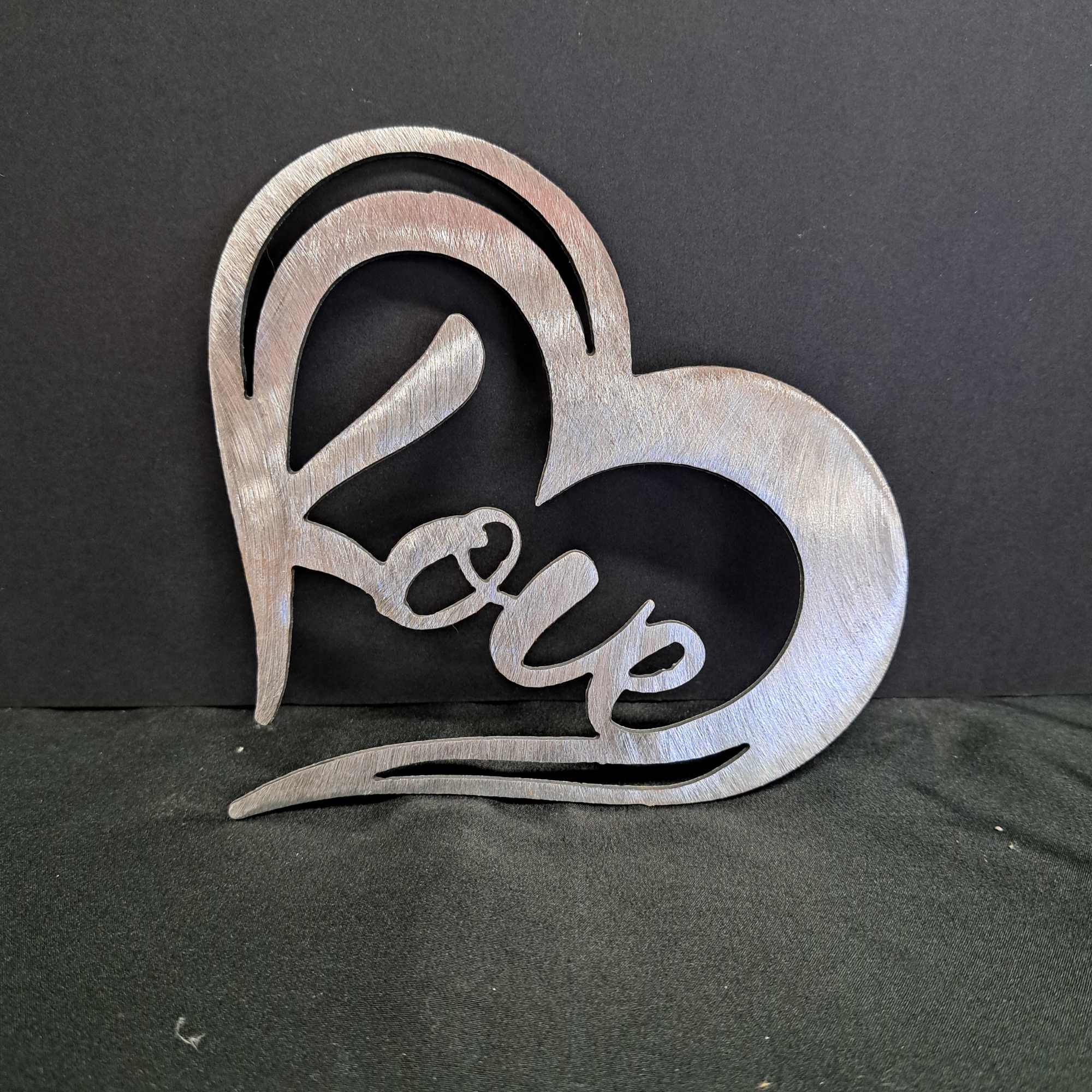 A brushed metal heart-shaped wall hanger that spells out "love" brings a