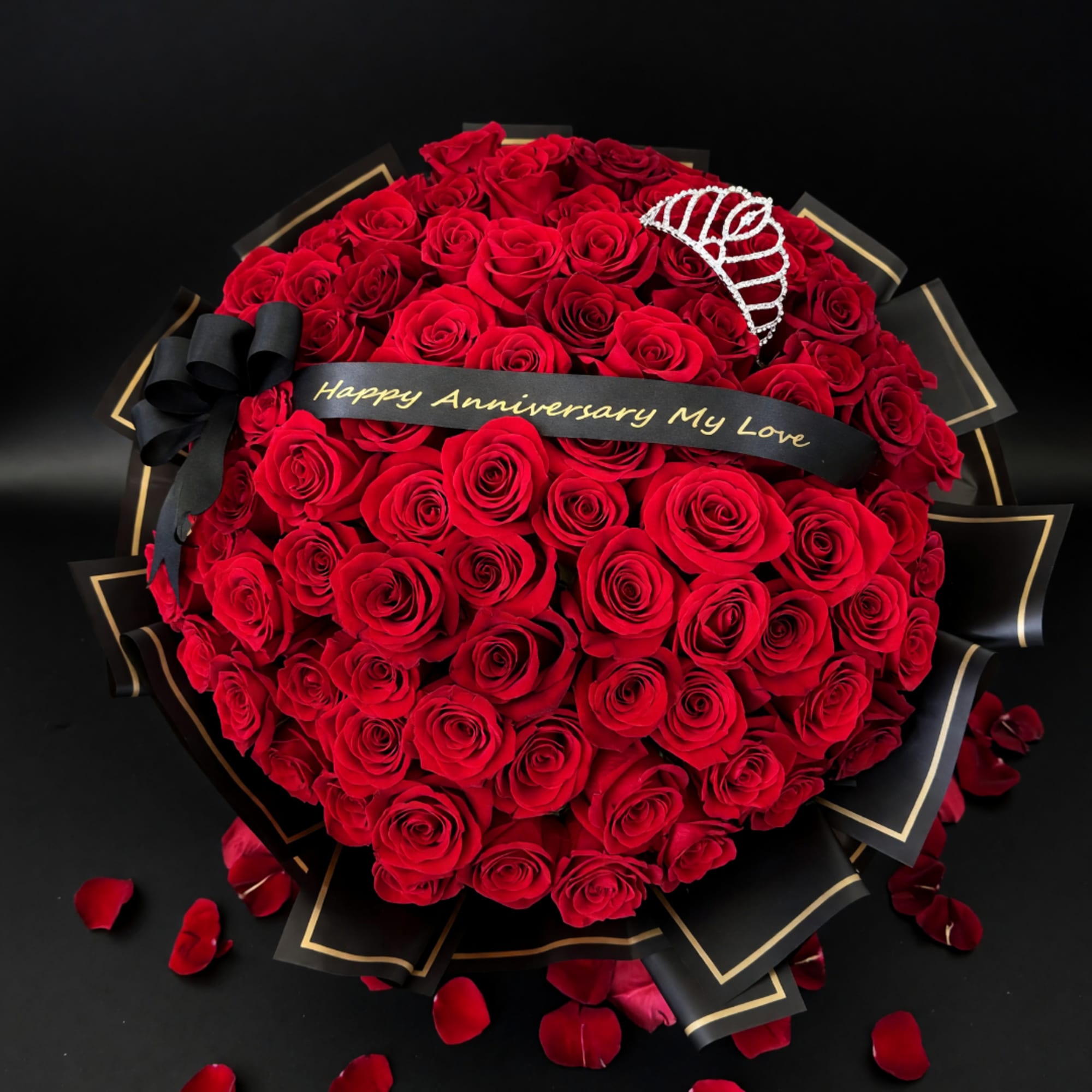Heart-shaped bouquet of red roses with a black anniversary ribbon and tiara