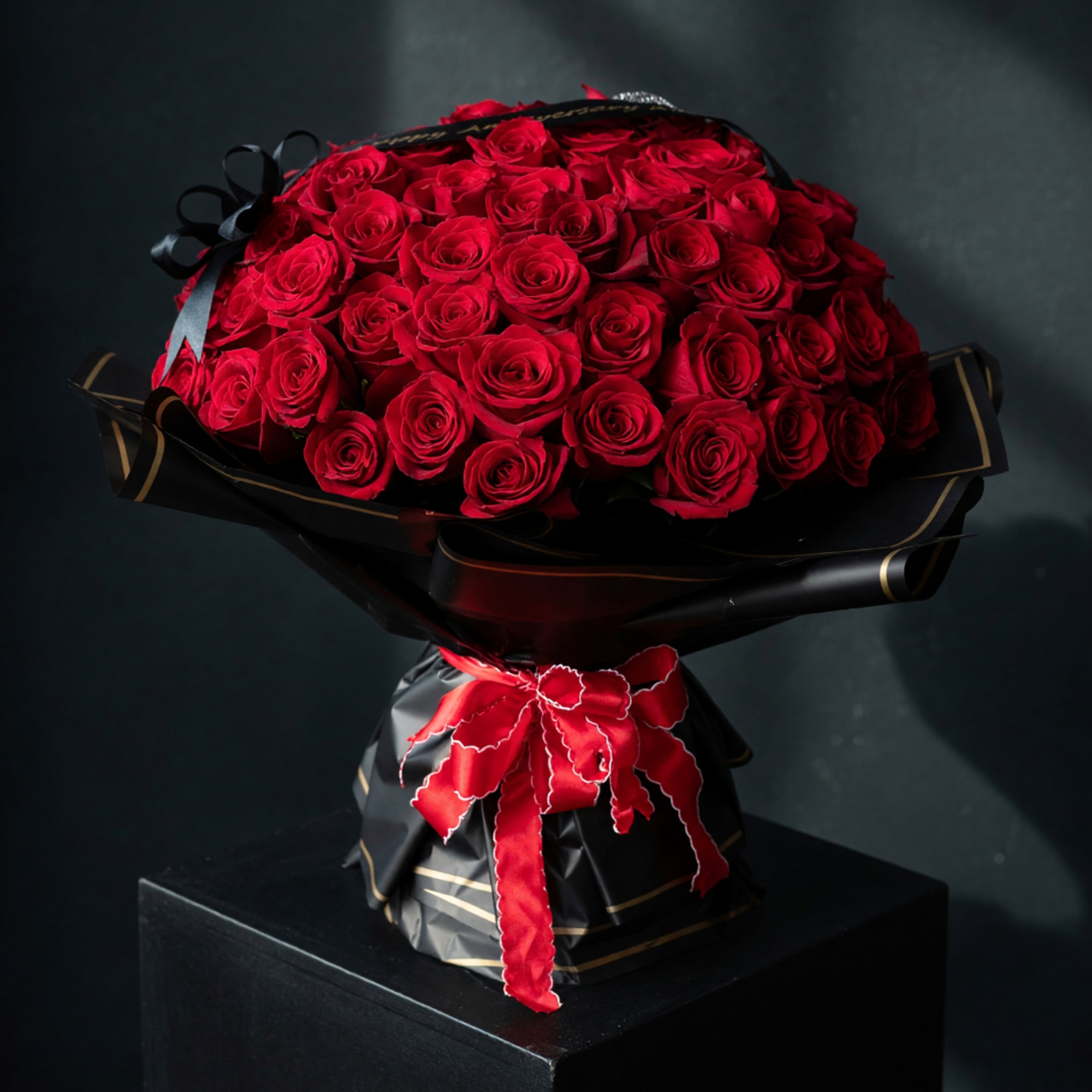 Bouquet of red roses wrapped in black paper with a red ribbon