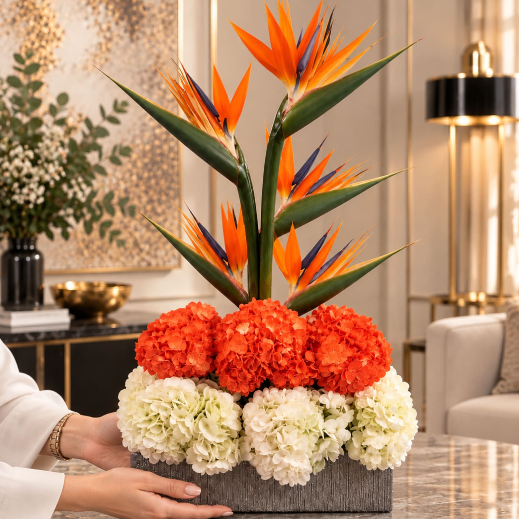 Tropical flower arrangement with orange bird-of-paradise and hydrangeas in a rectangular vase