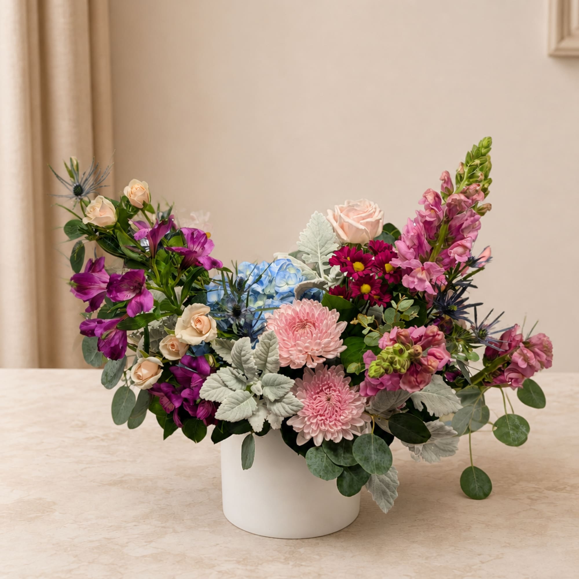 Mixed bouquet in a white vase with pink, purple, and blue flowers