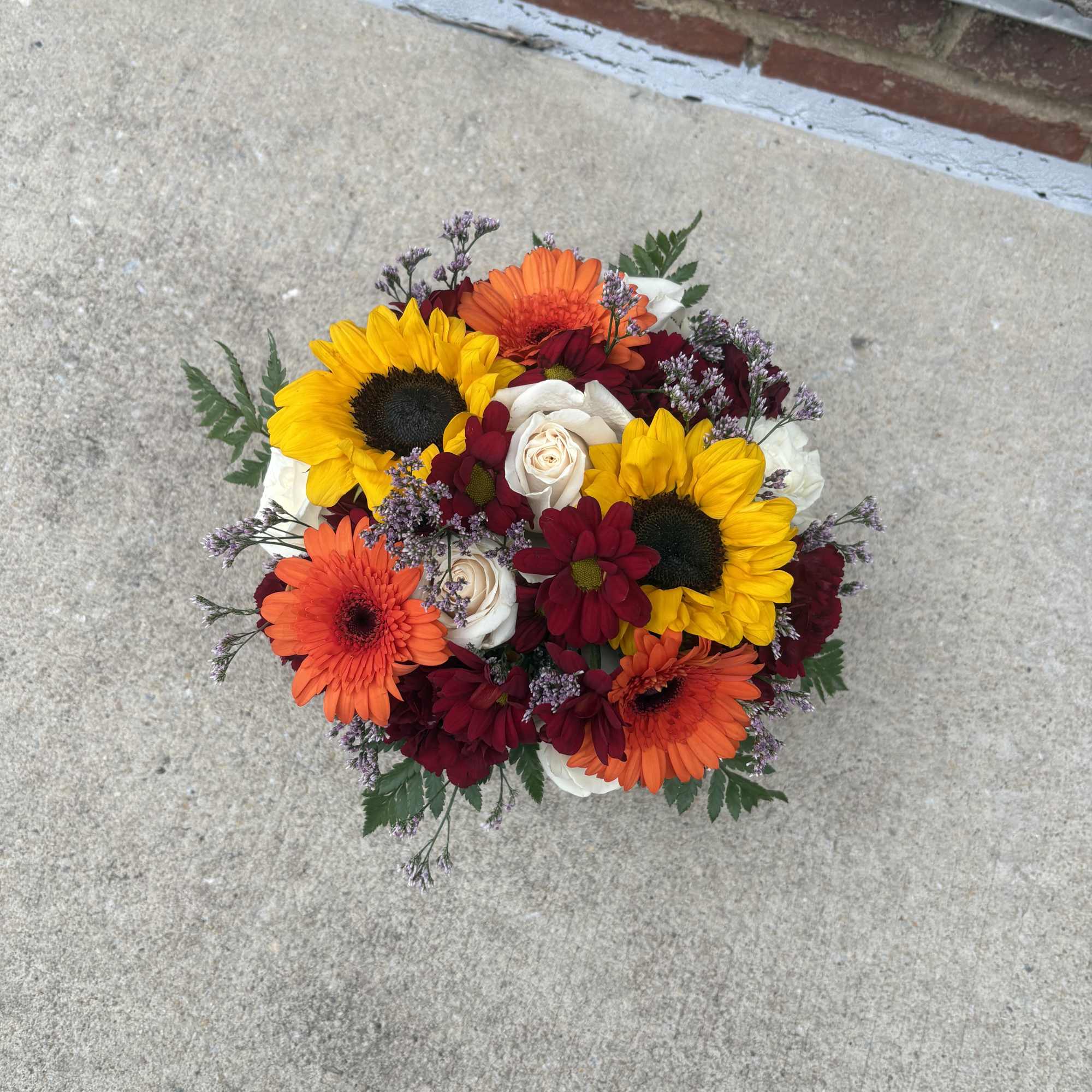 Mixed bouquet with sunflowers, orange gerbera daisies, white roses, and burgundy blooms