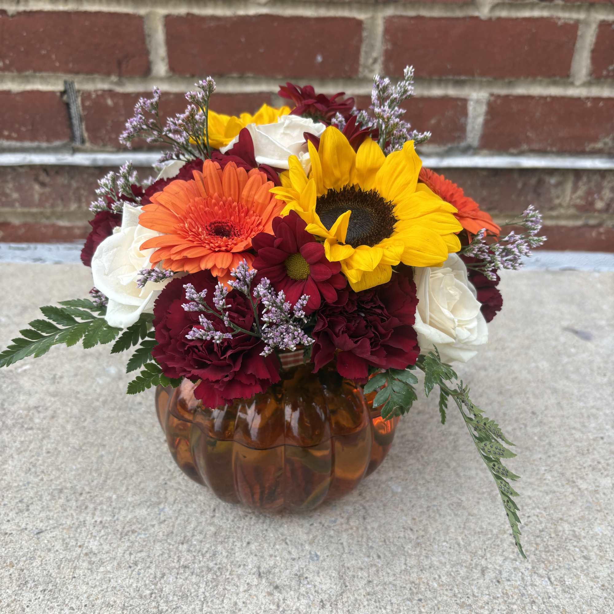 Mixed bouquet in an amber pumpkin vase with sunflowers and gerbera daisies