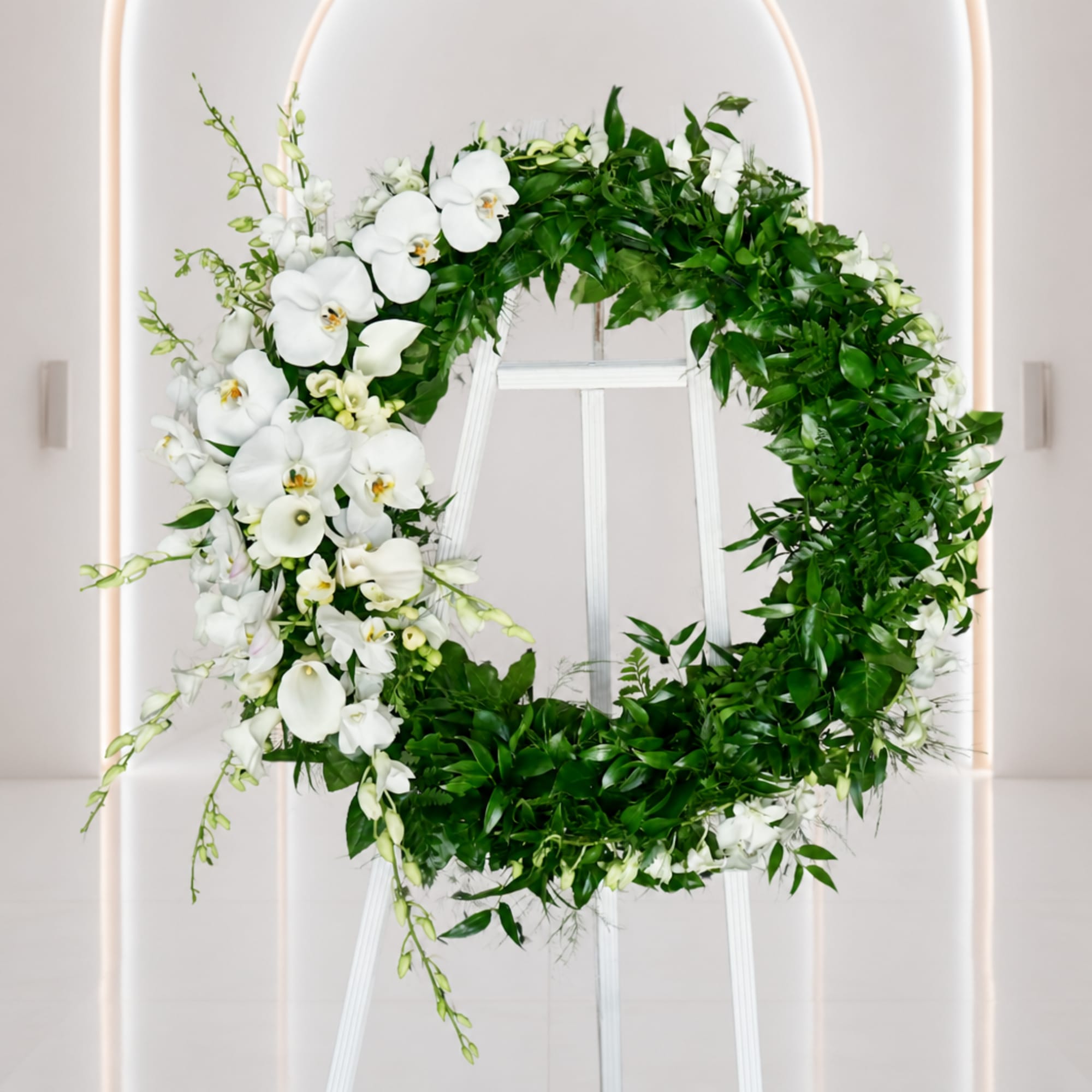 White orchid and greenery wreath on a white easel
