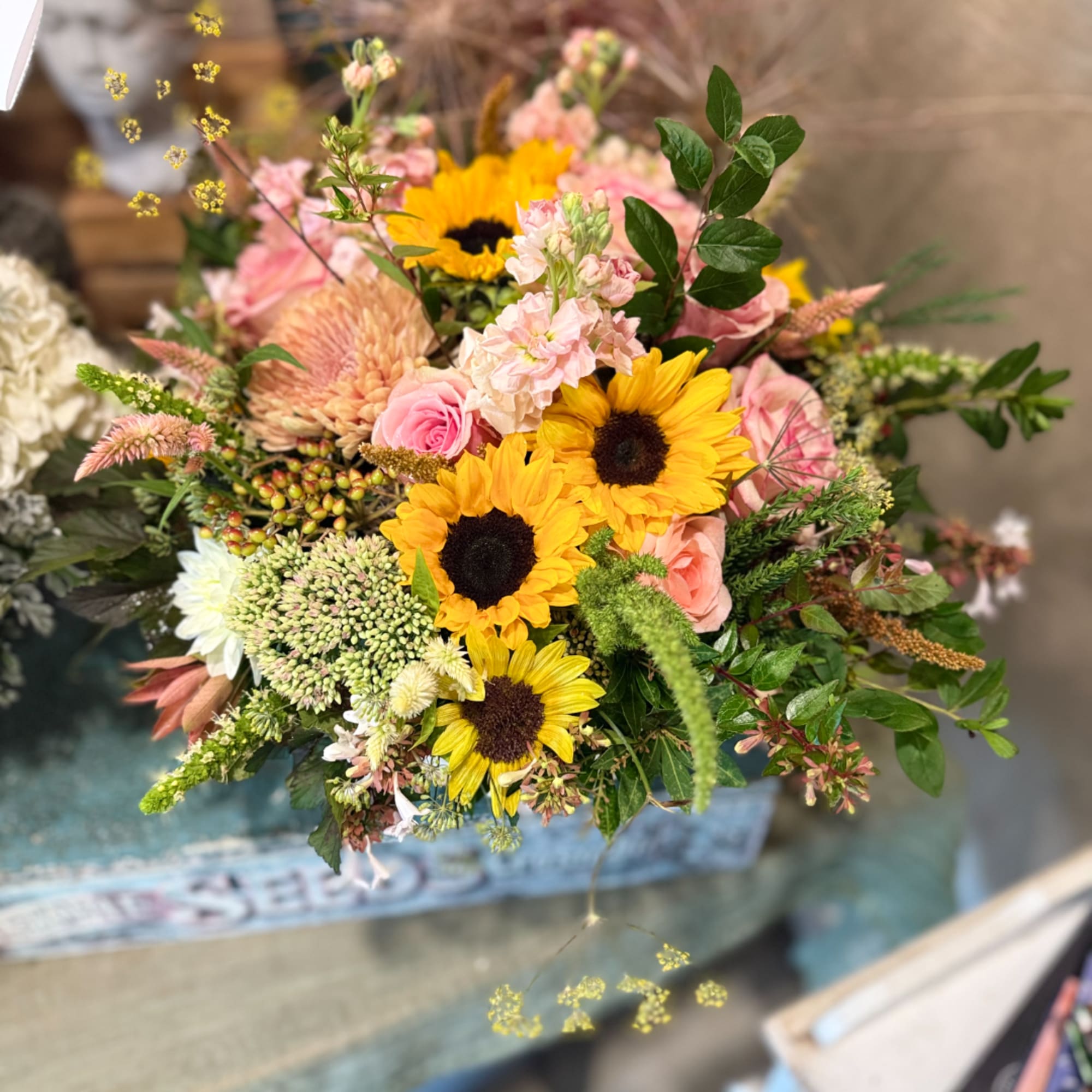 Mixed bouquet with sunflowers, pink roses, and pale blooms