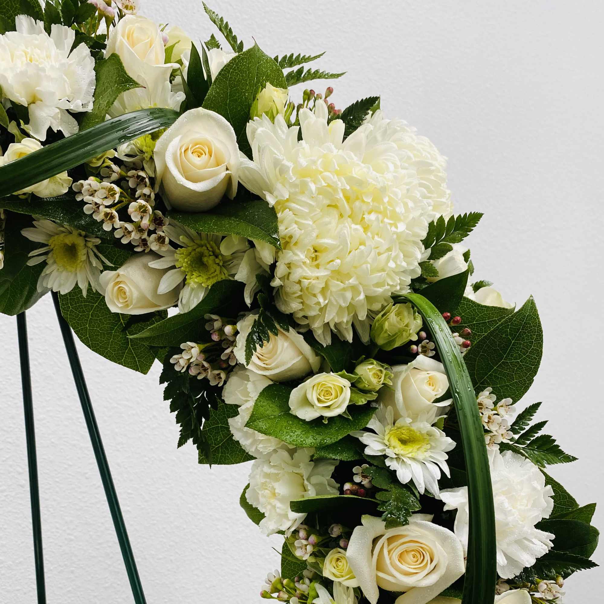 White floral arrangement with roses and chrysanthemums on a curved stand