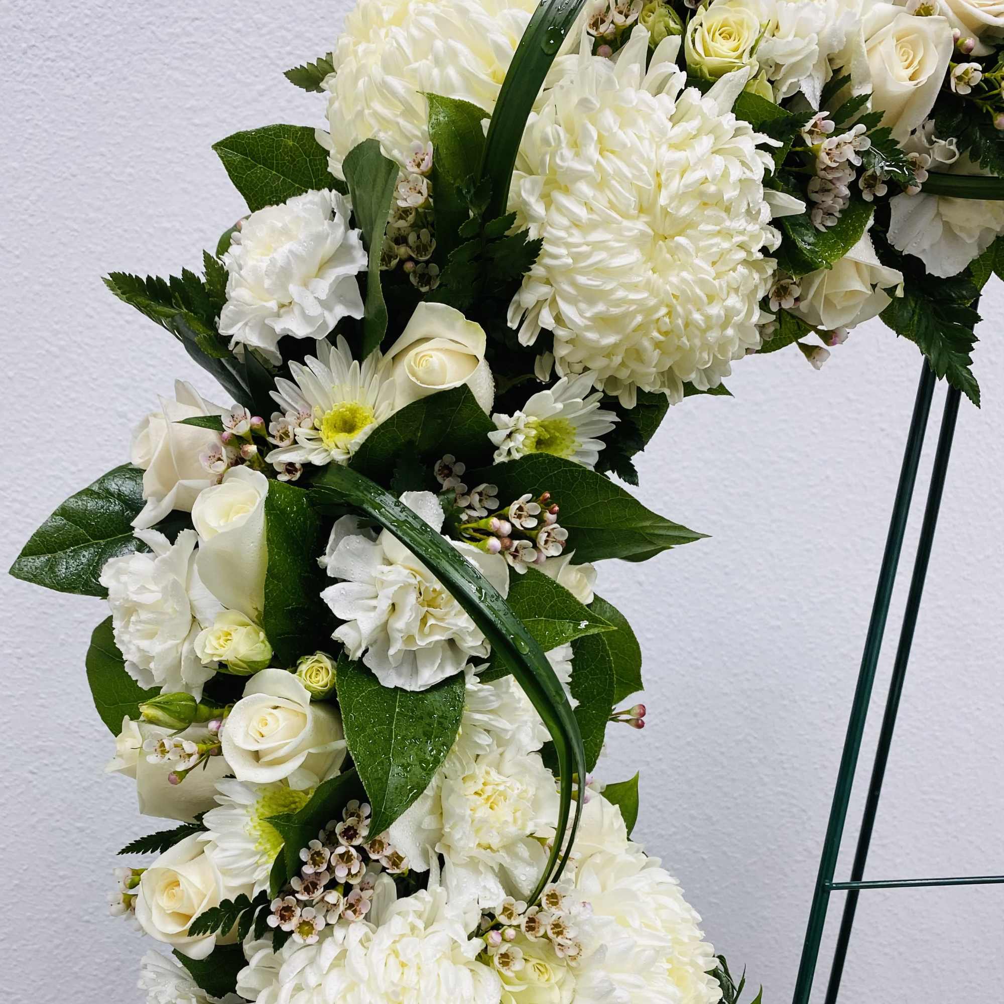 White floral arrangement with roses, chrysanthemums, and carnations on a stand