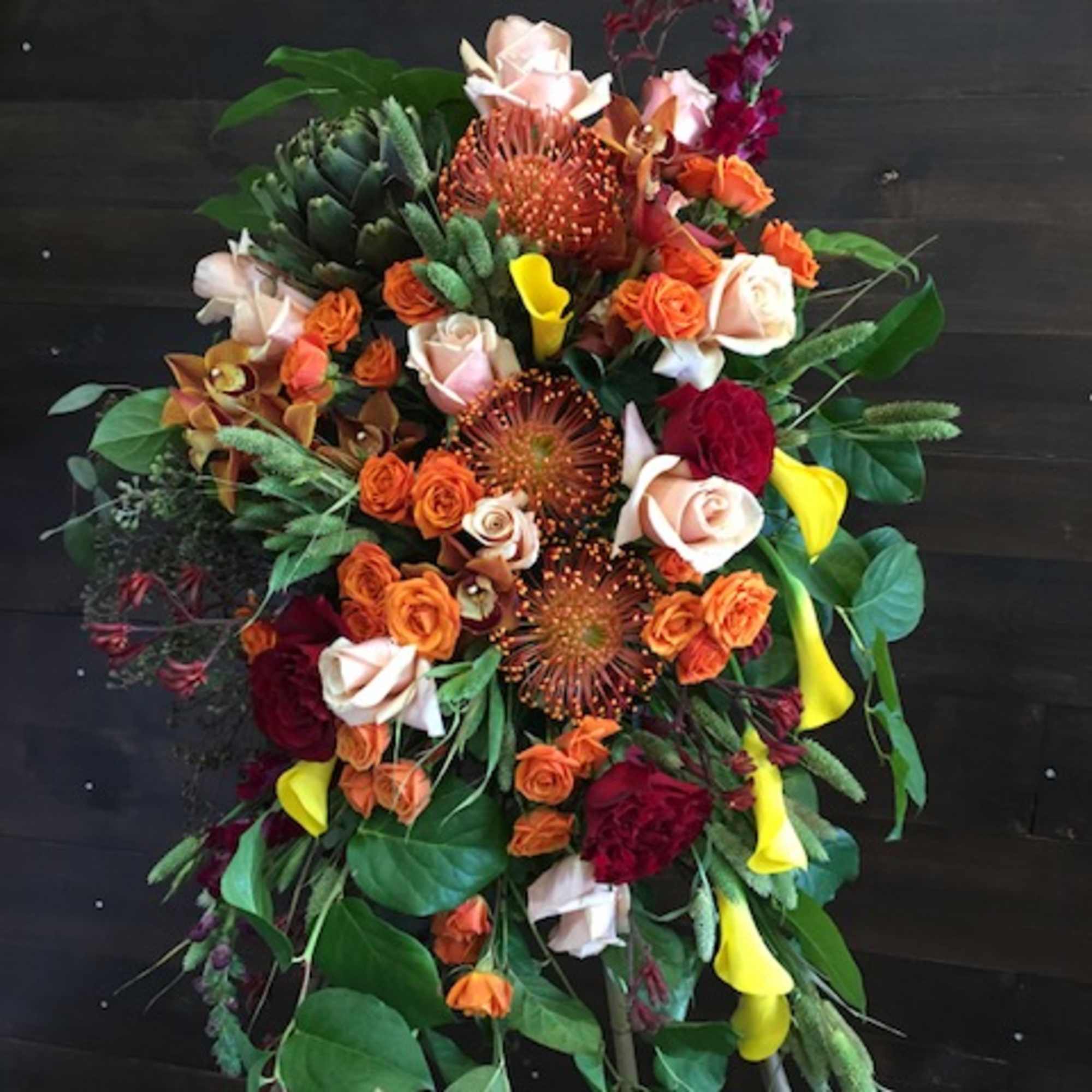 Large standing floral spray with orange, red, yellow, and pale pink blooms