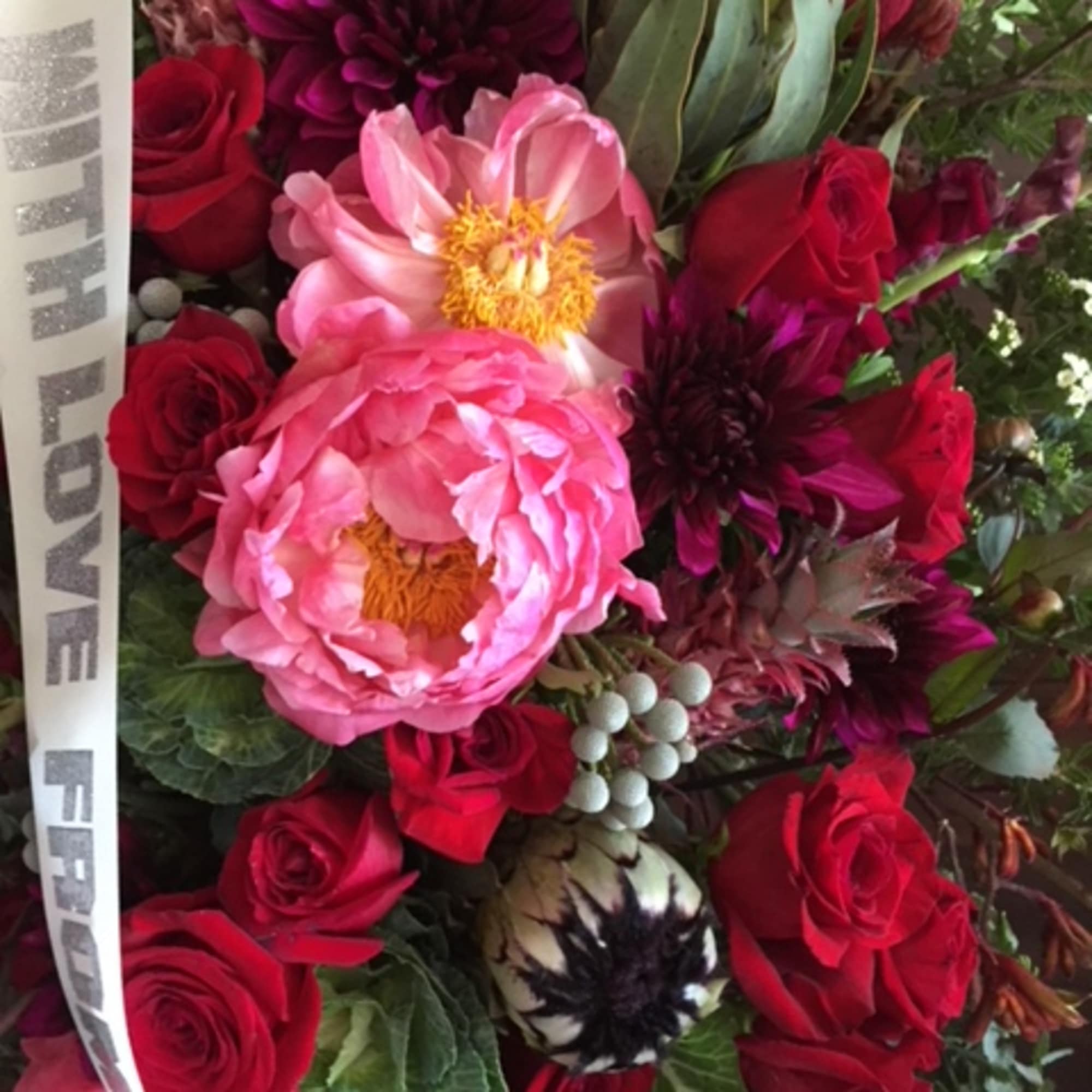 Bouquet of pink peonies and red roses with a ribbon