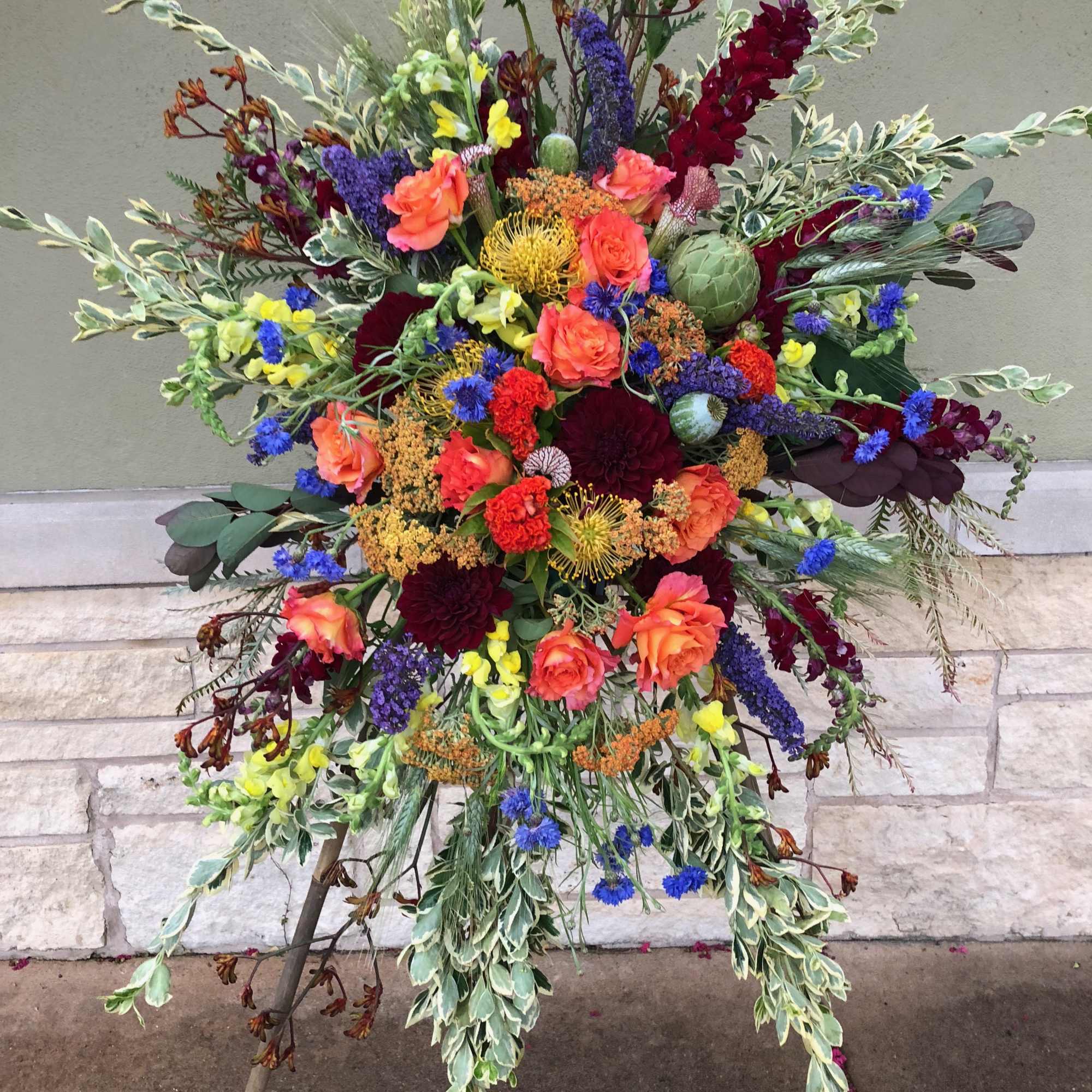 Large standing floral spray with orange, red, blue, and yellow blooms
