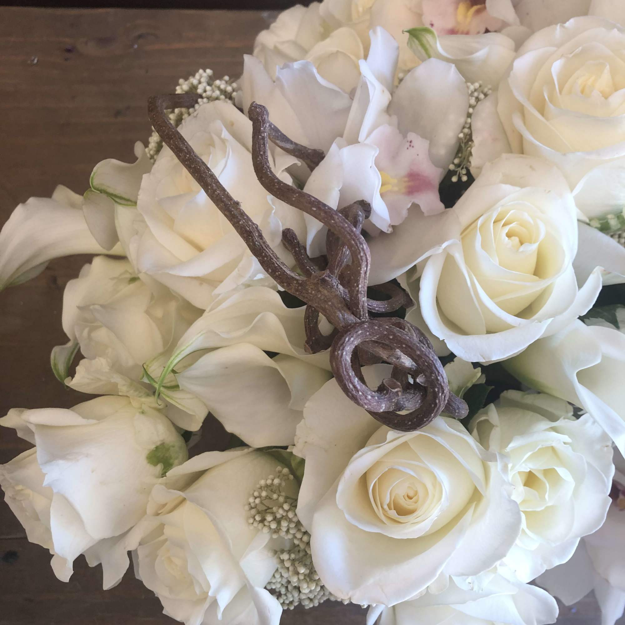 White rose and calla lily bouquet with a decorative twig accent