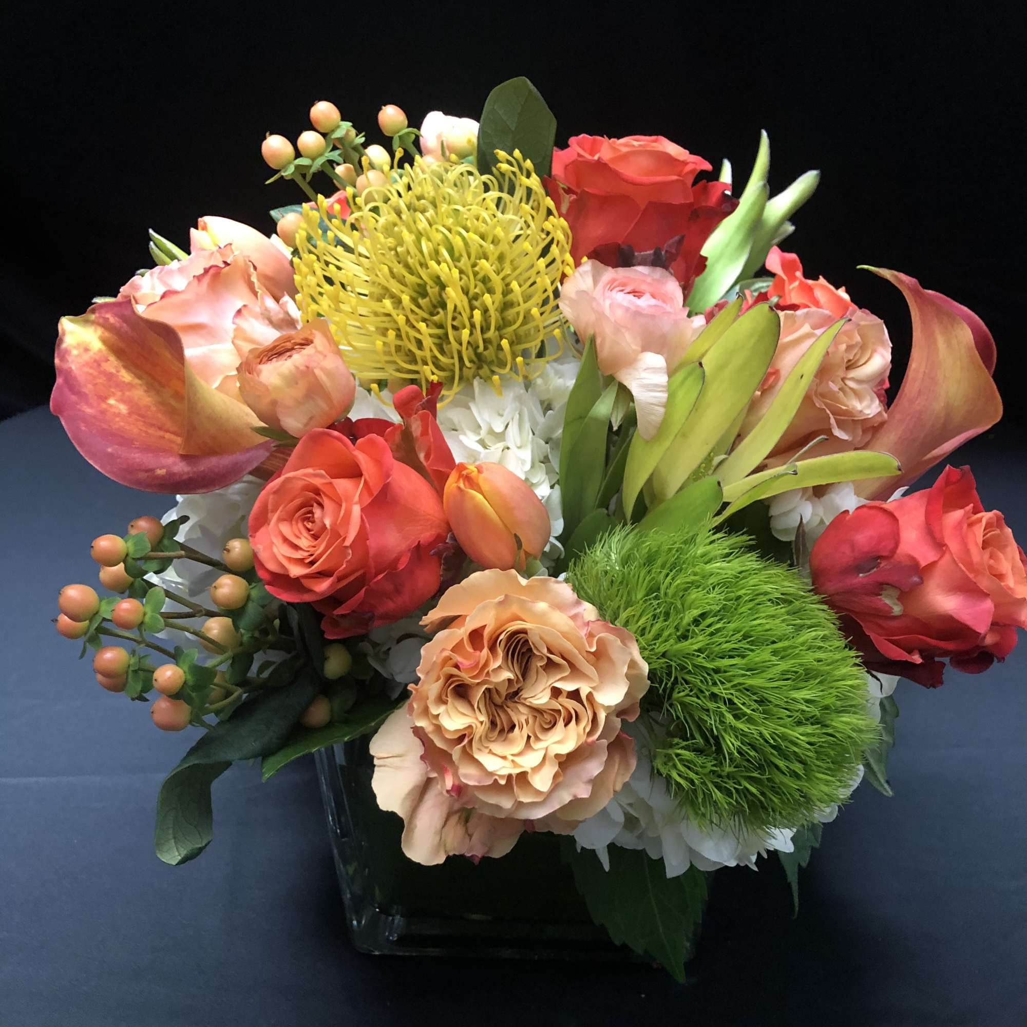 Mixed bouquet in a square glass vase with roses and calla lilies