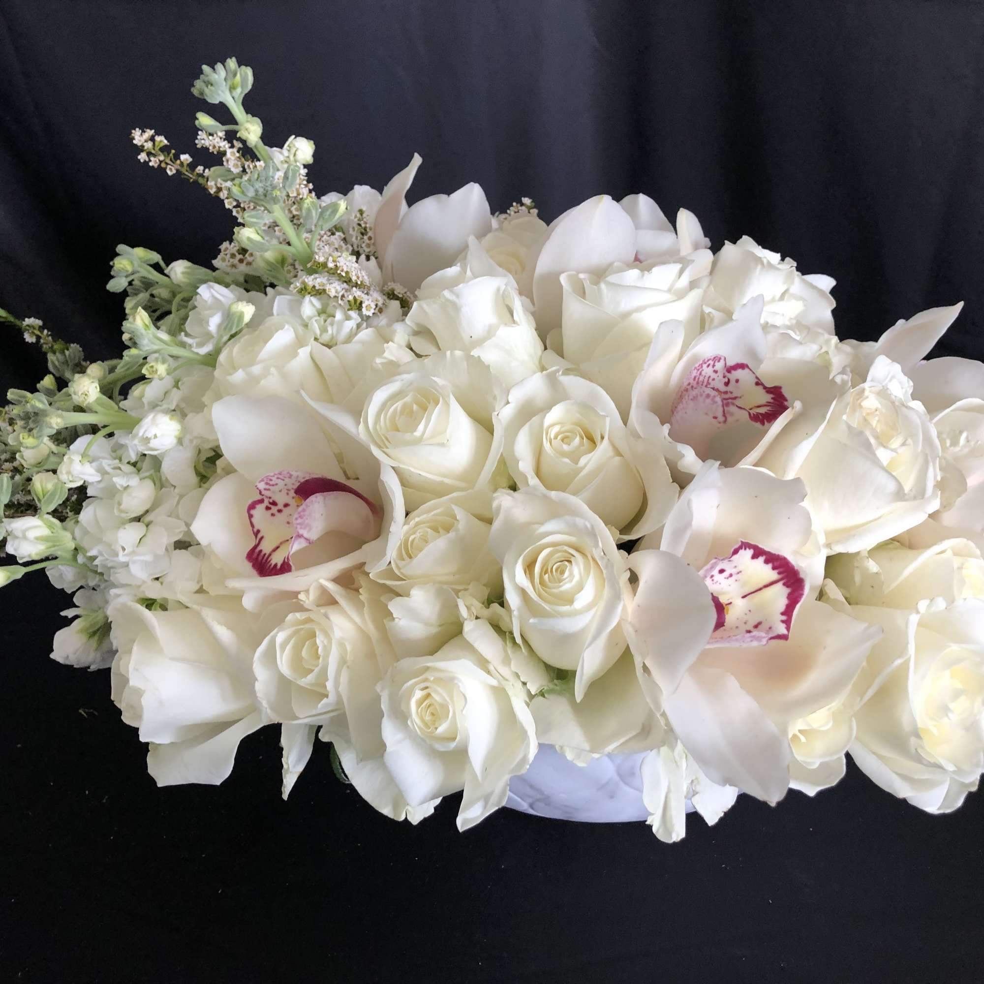 White rose and orchid bouquet with pale filler flowers