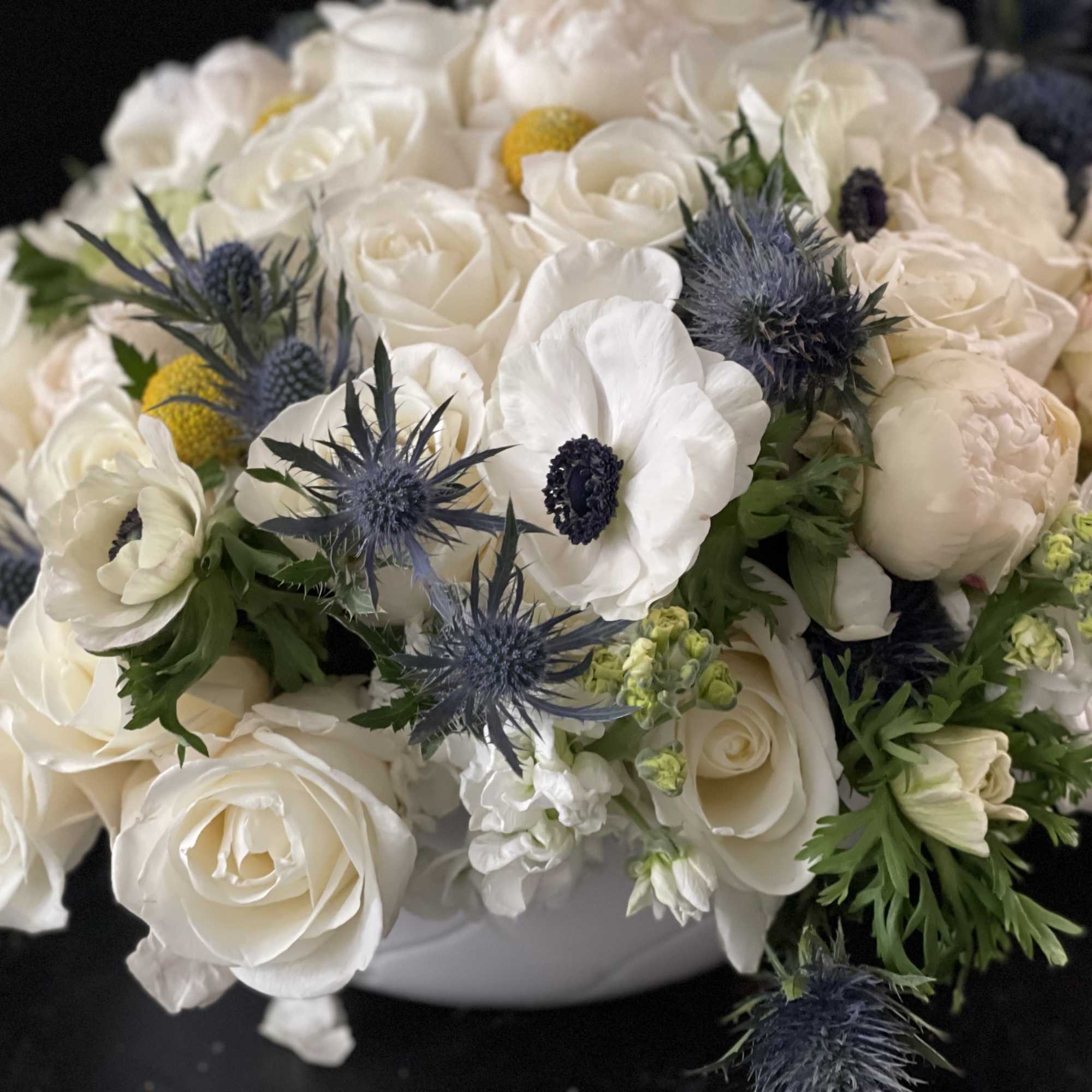 White rose bouquet with blue thistle and small yellow accents